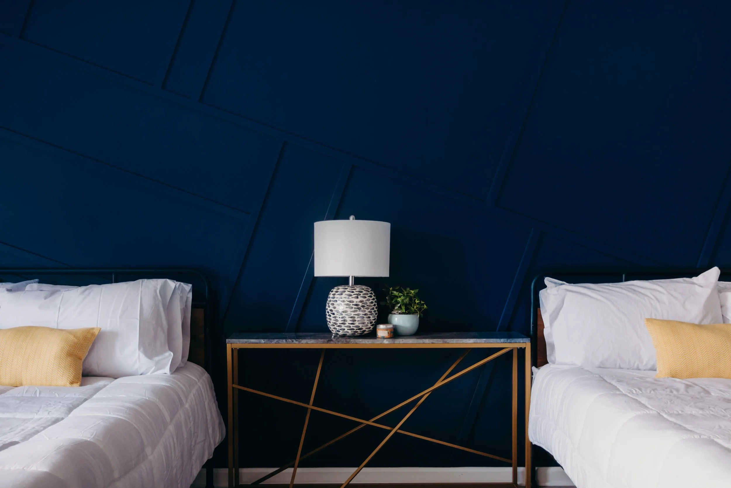 Reimagined boutique guest room interior at Lakeside Inn showcasing a dark blue accent wall, modern bedside table, and plush bedding.