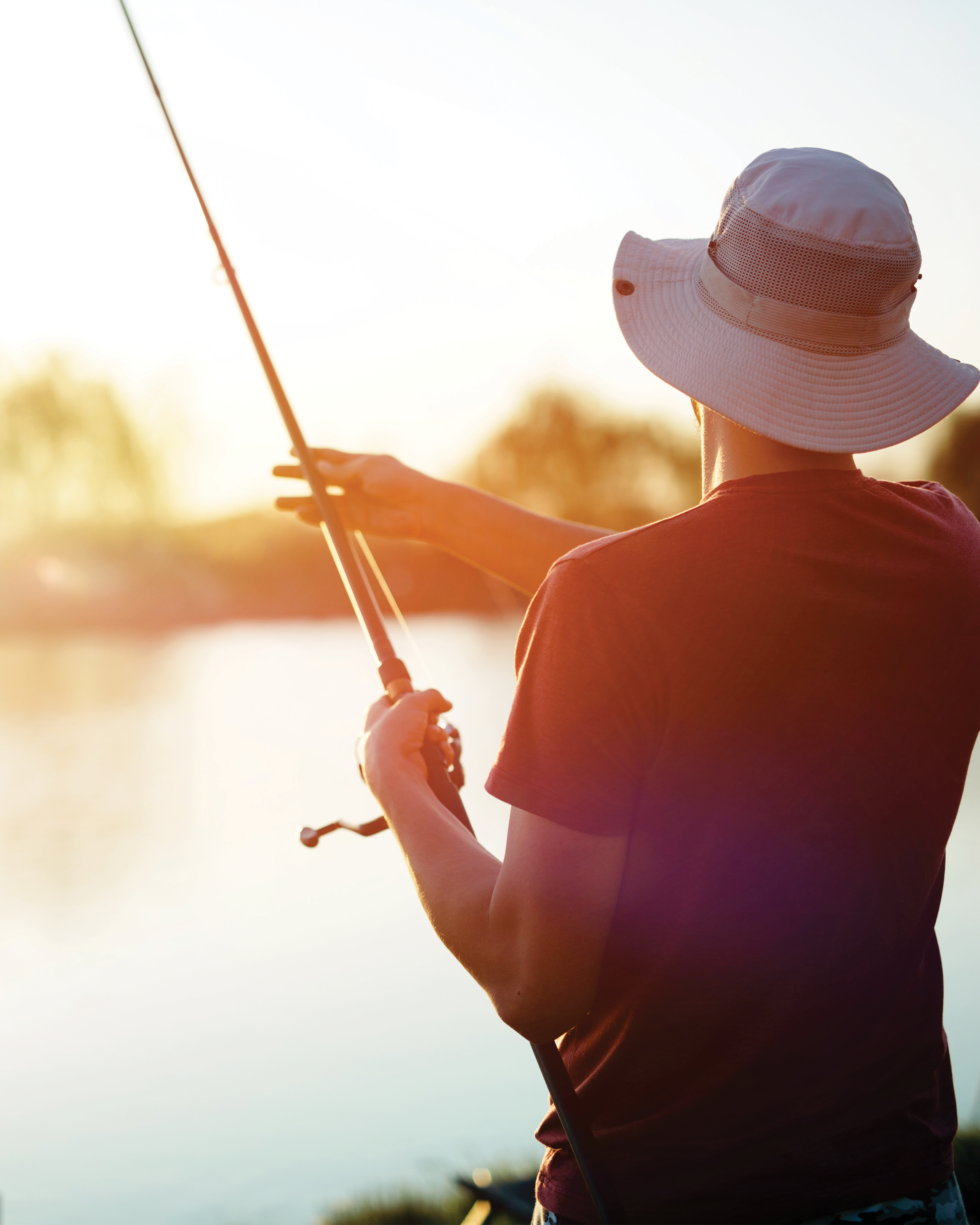 An angler holding a fishing rod over the water during an early morning sunrise on Dale Hollow Lake.