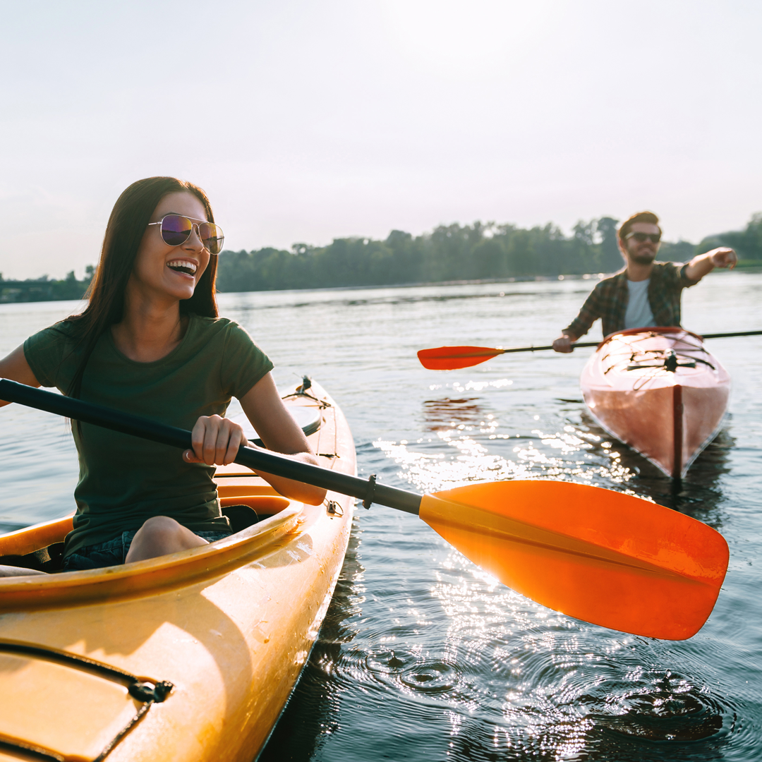 Couple paddling tandem yellow and red kayaks across the calm morning waters of Dale Hollow Lake in the fall