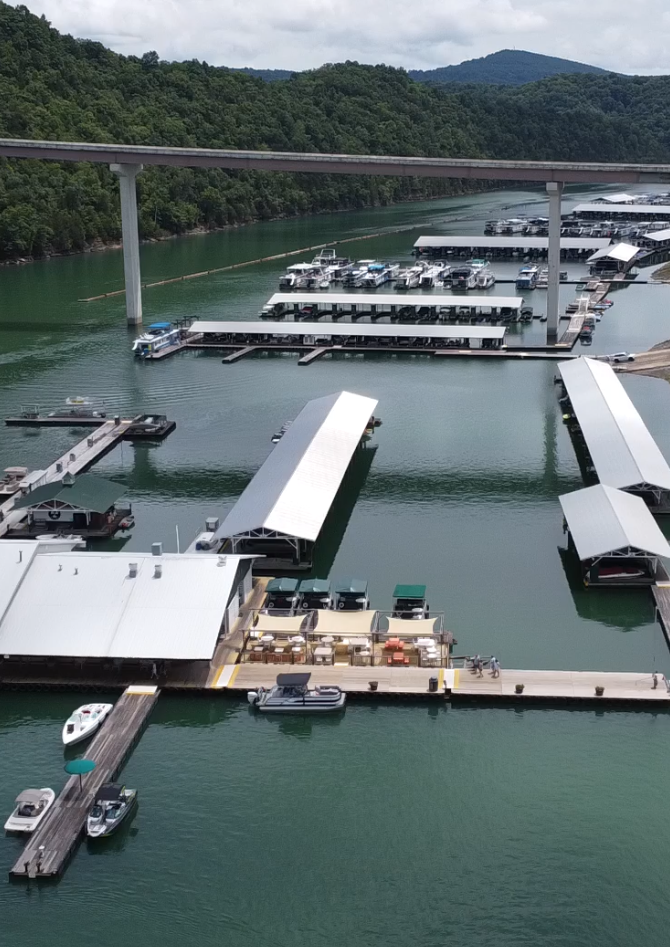 Aerial view of a lakeside marina docks and public boat launch ramps surrounded by forested hills at Dale Hollow Lake.
