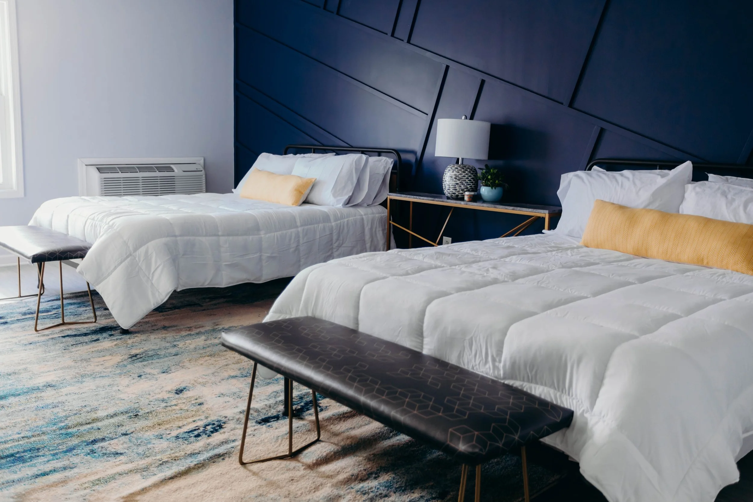 Premium double queen room setup at Lakeside Inn featuring modern design accents, a luxury rug, and a seating bench.