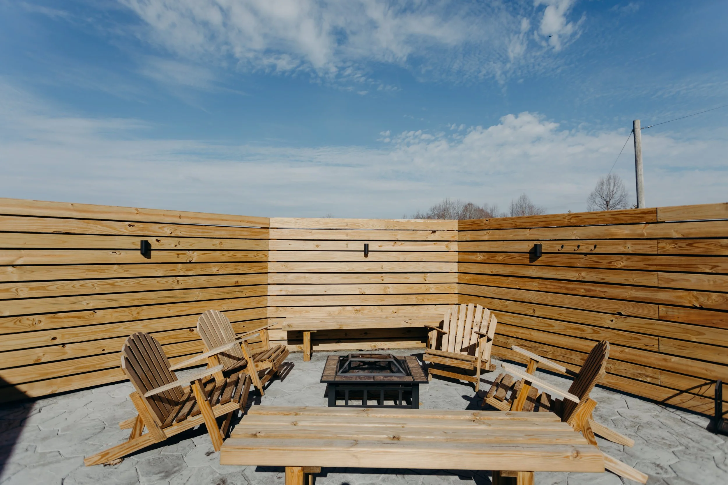 Cozy outdoor lounge area patio at Lakeside Inn featuring comfortable Adirondack chairs arranged around a warm fire pit for guests to enjoy the evening.