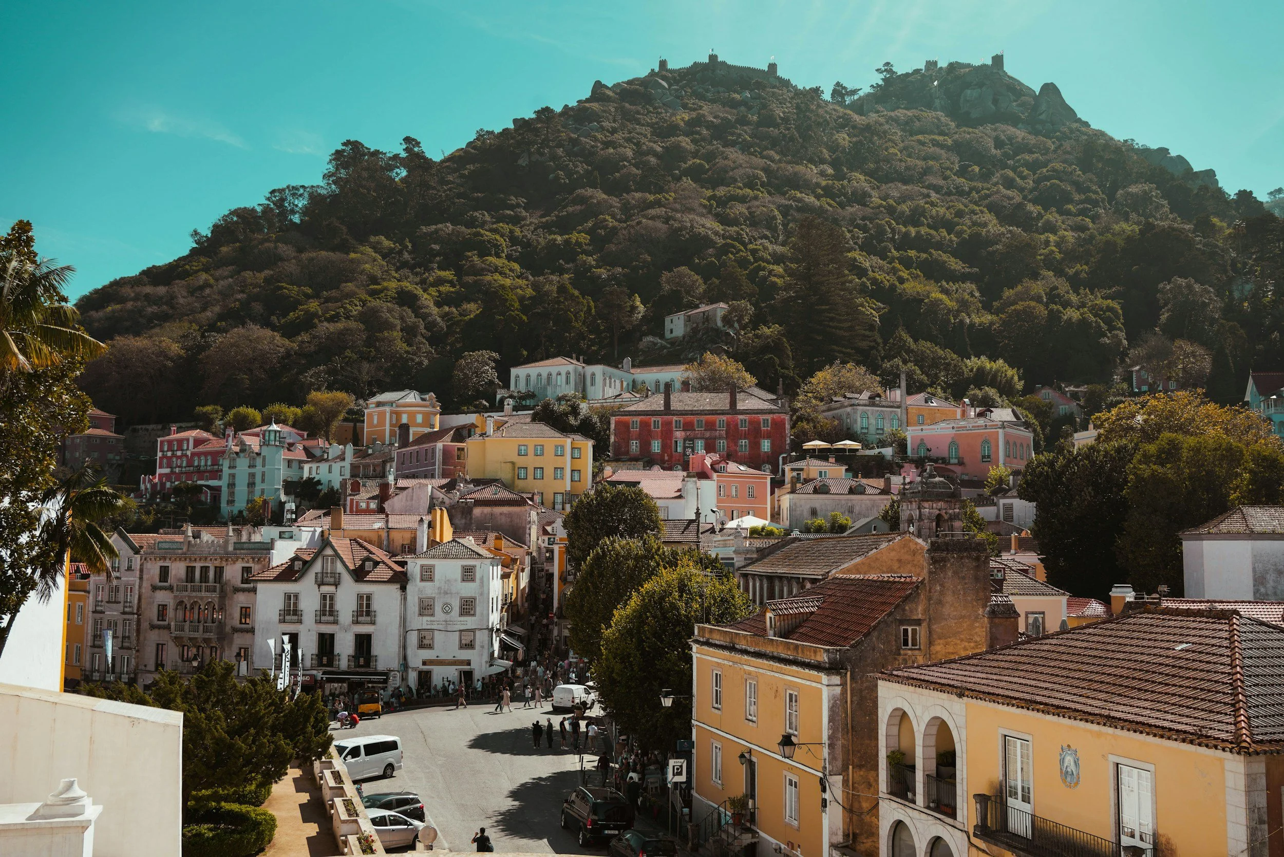 A scenic view of a hillside city with colorful buildings and a fortress on top of the hill.