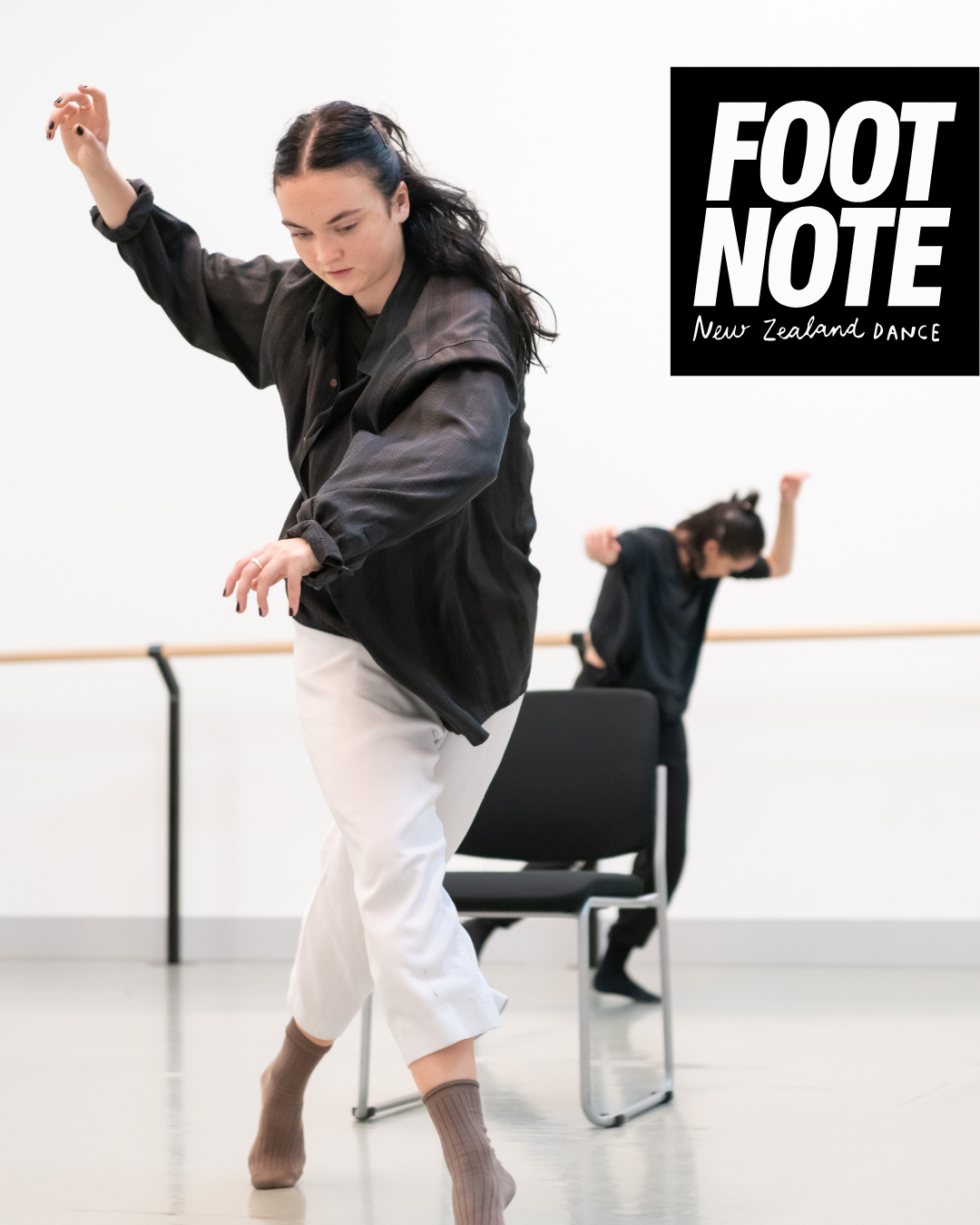 A dancer moving through space with one leg crossed over in a crossed step in front of themself with arms reaching to the right and eyeline down. Includes footnote logo