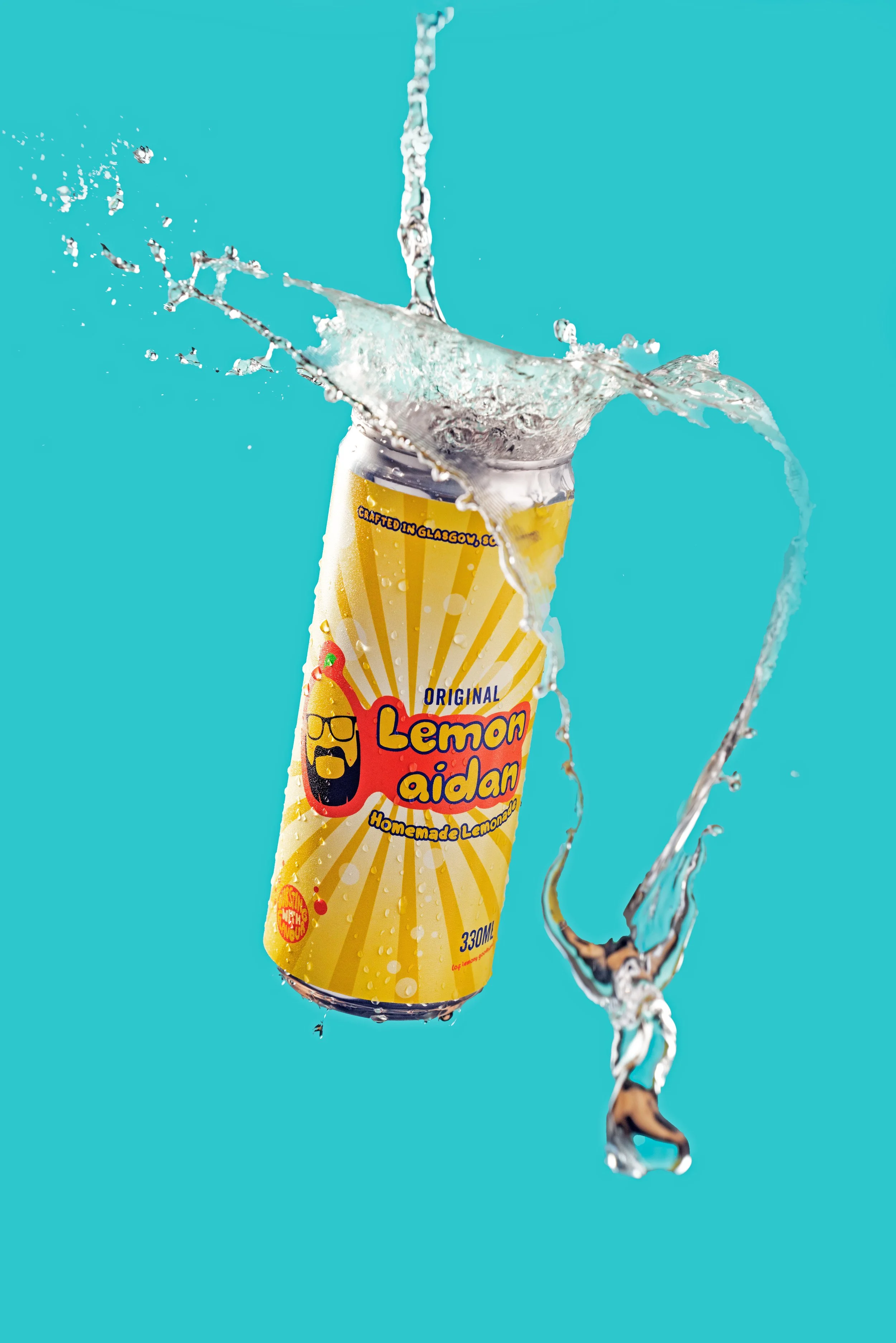 A can of Lemon Aidan homemade lemonade splashing into water against a turquoise background.