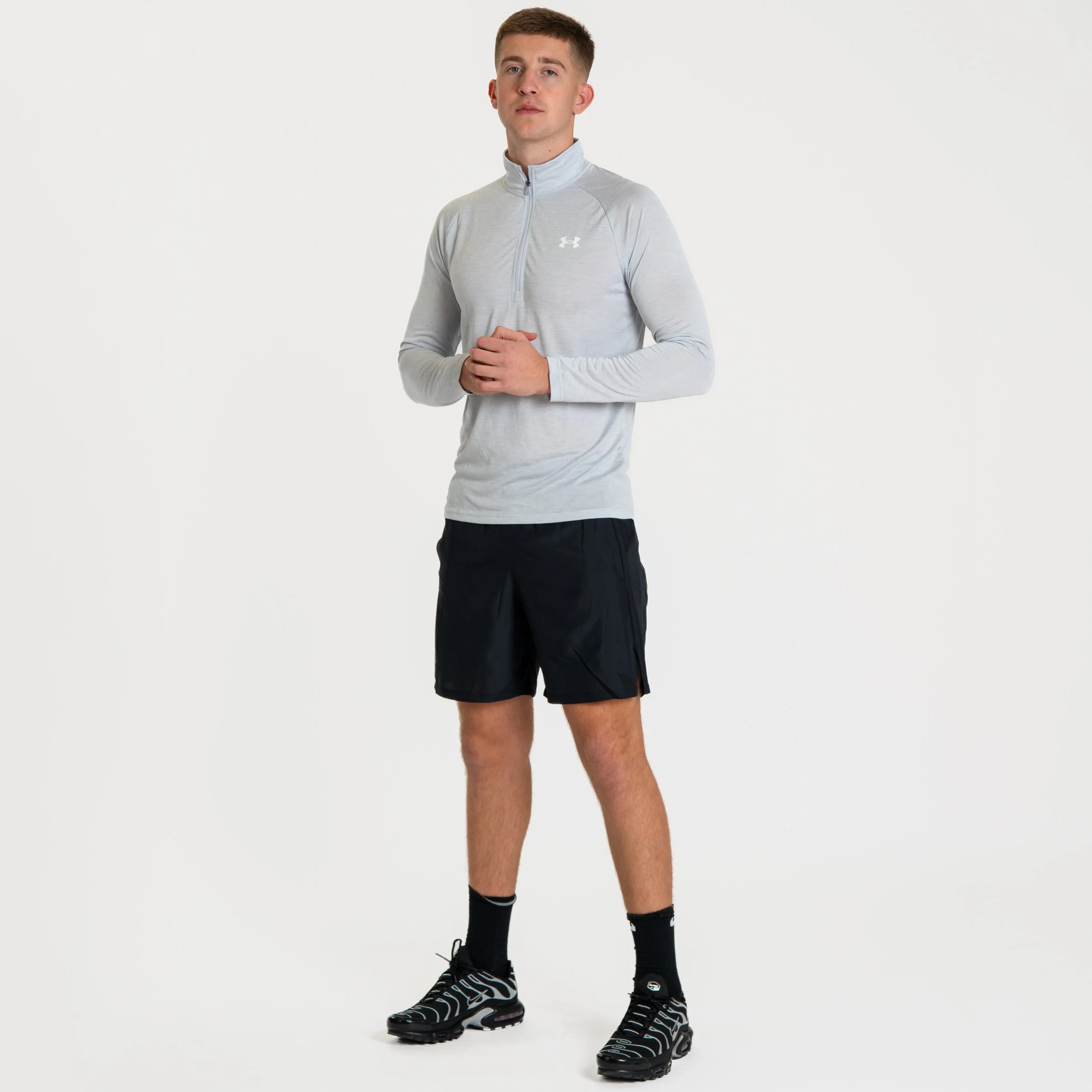 Young man dressed in athletic clothing, standing with hands clasped in front, against a plain white background.