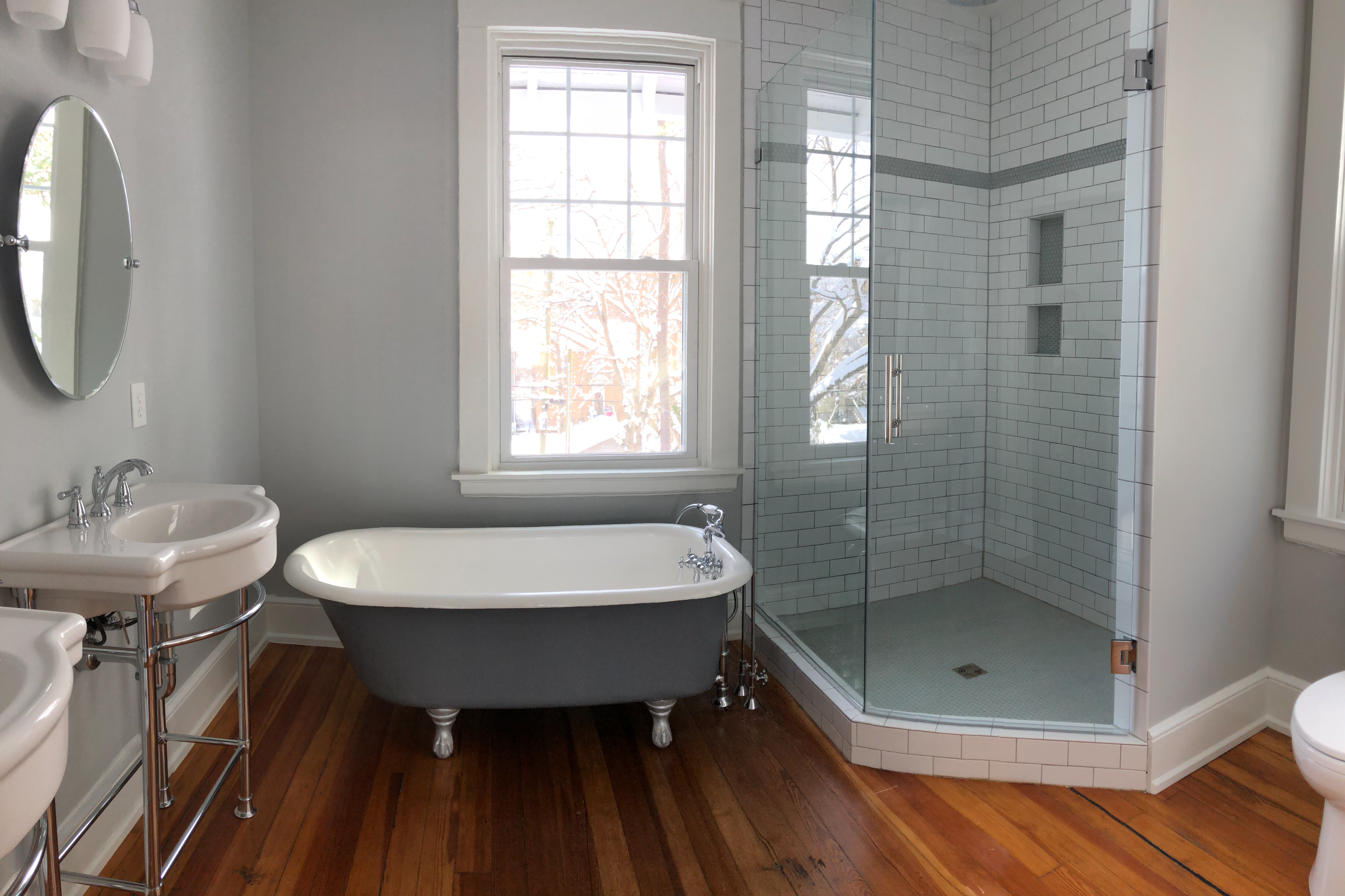 Primary bathroom with glass shower enclosure and restored clawfoot tub.