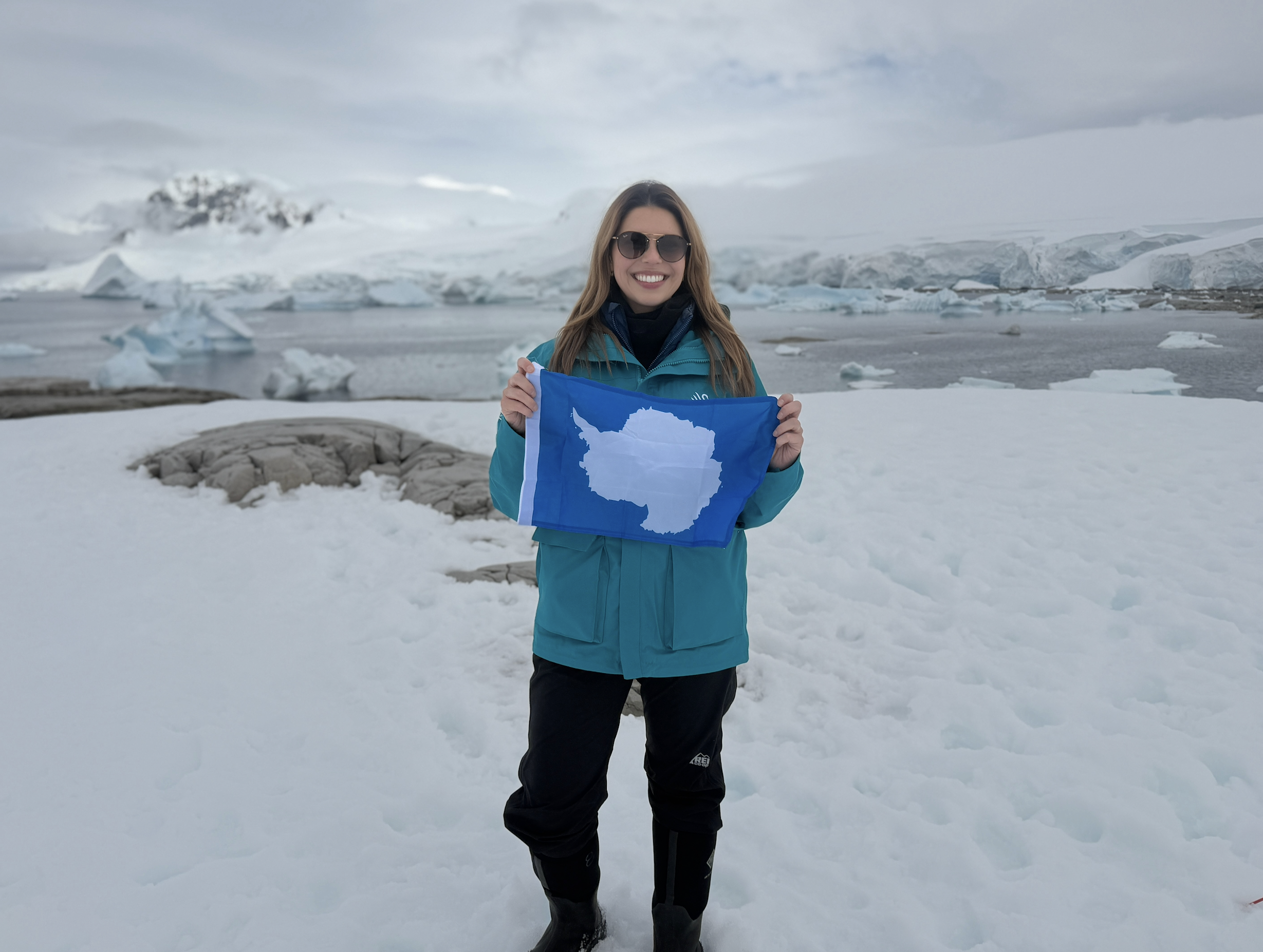 Laura Poe standing on the continent of Antarctica hold the flag.