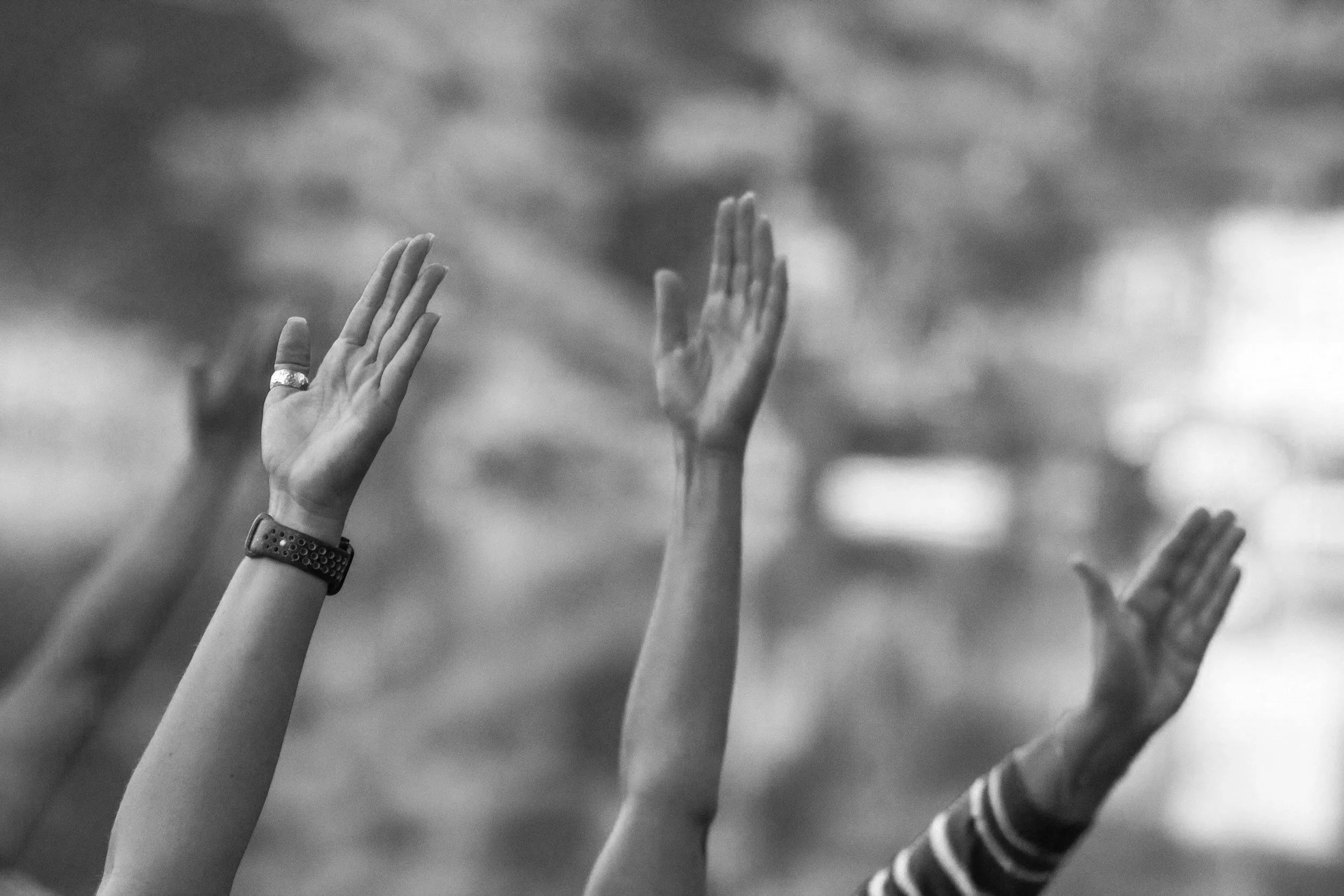 Black and white image of raised stretching hands.