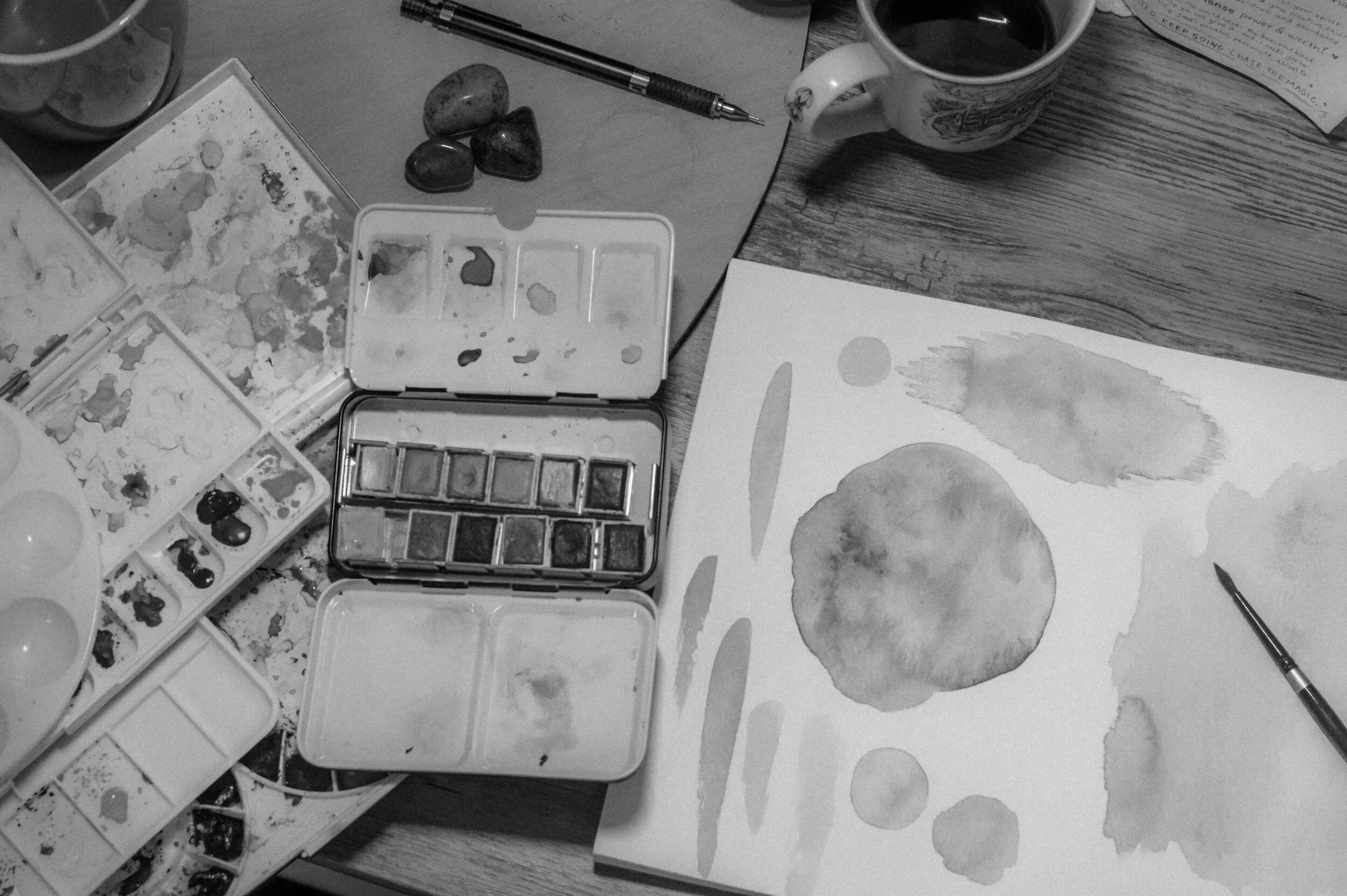 Black and white picture of art supplies including water color and paper for art therapy.