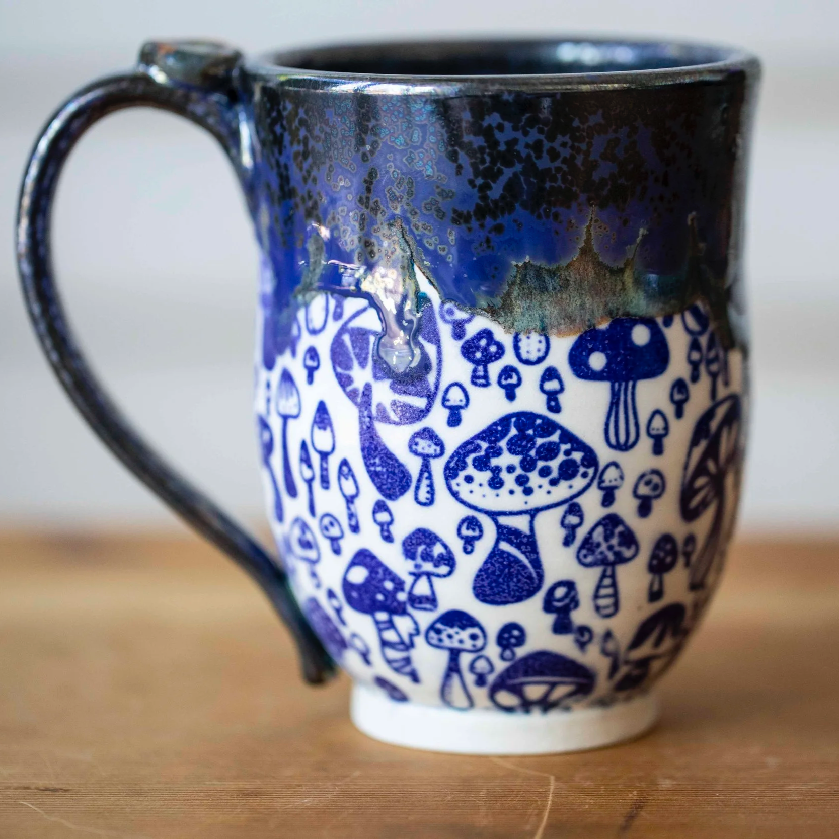 Ceramic mug with a mushroom pattern and blue, black, and white glaze