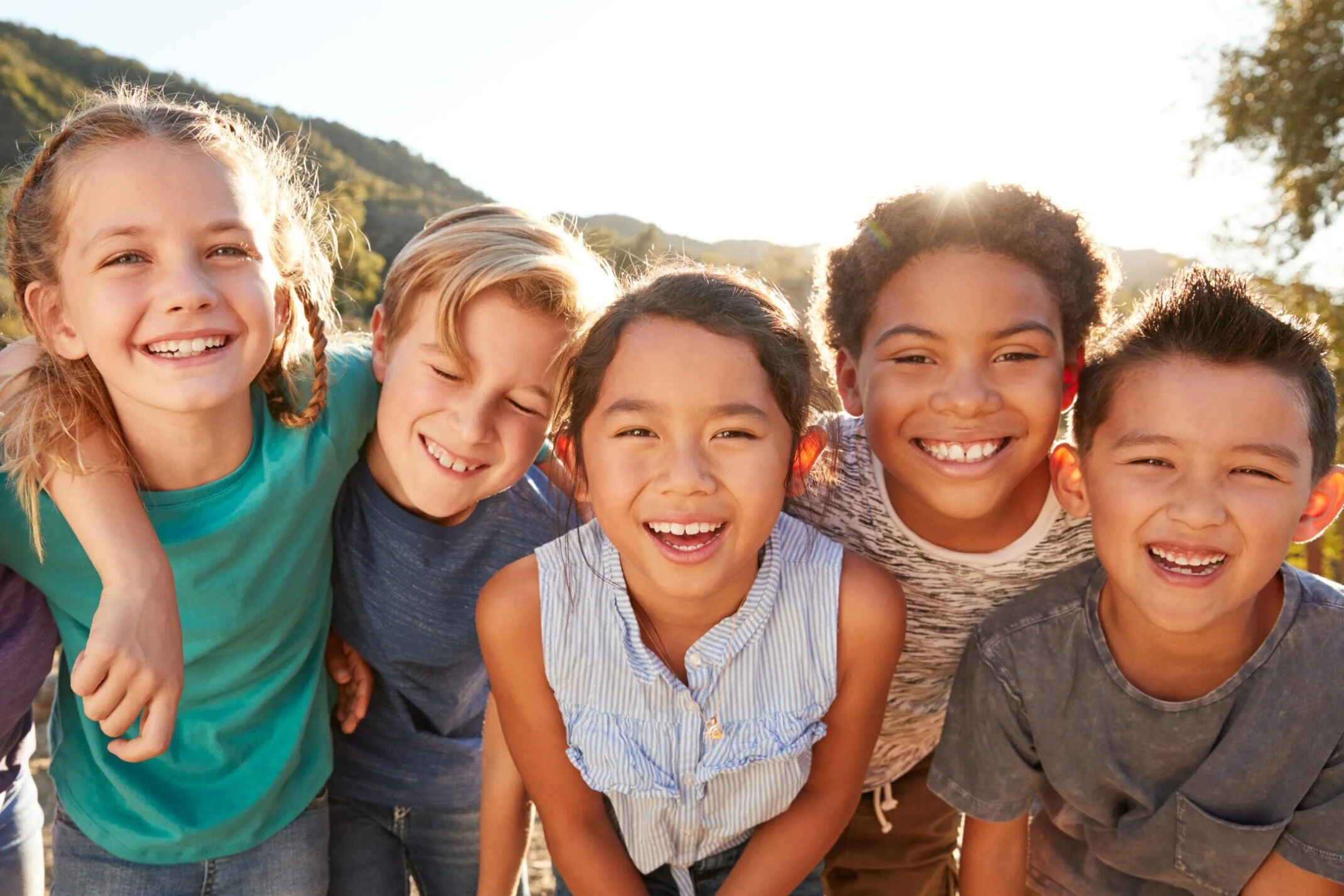 Group+of+smiling+children+looking+at+camera+with+mountain+range+behind+them+.jpg