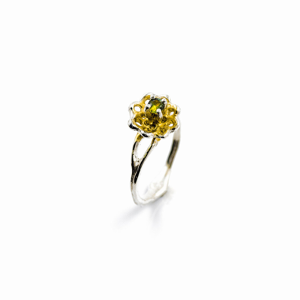 A yellow-green Australian sapphire extends from a golden surfaced silver fan. Luke Maninov