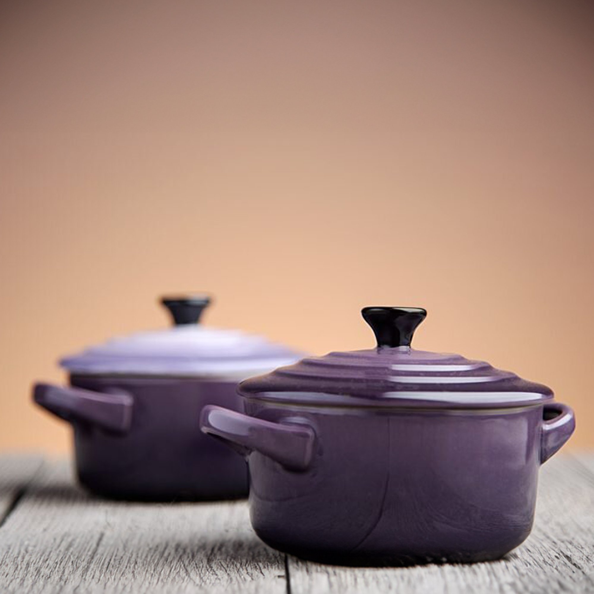  Purple cookware on a wood table and a light orange background 