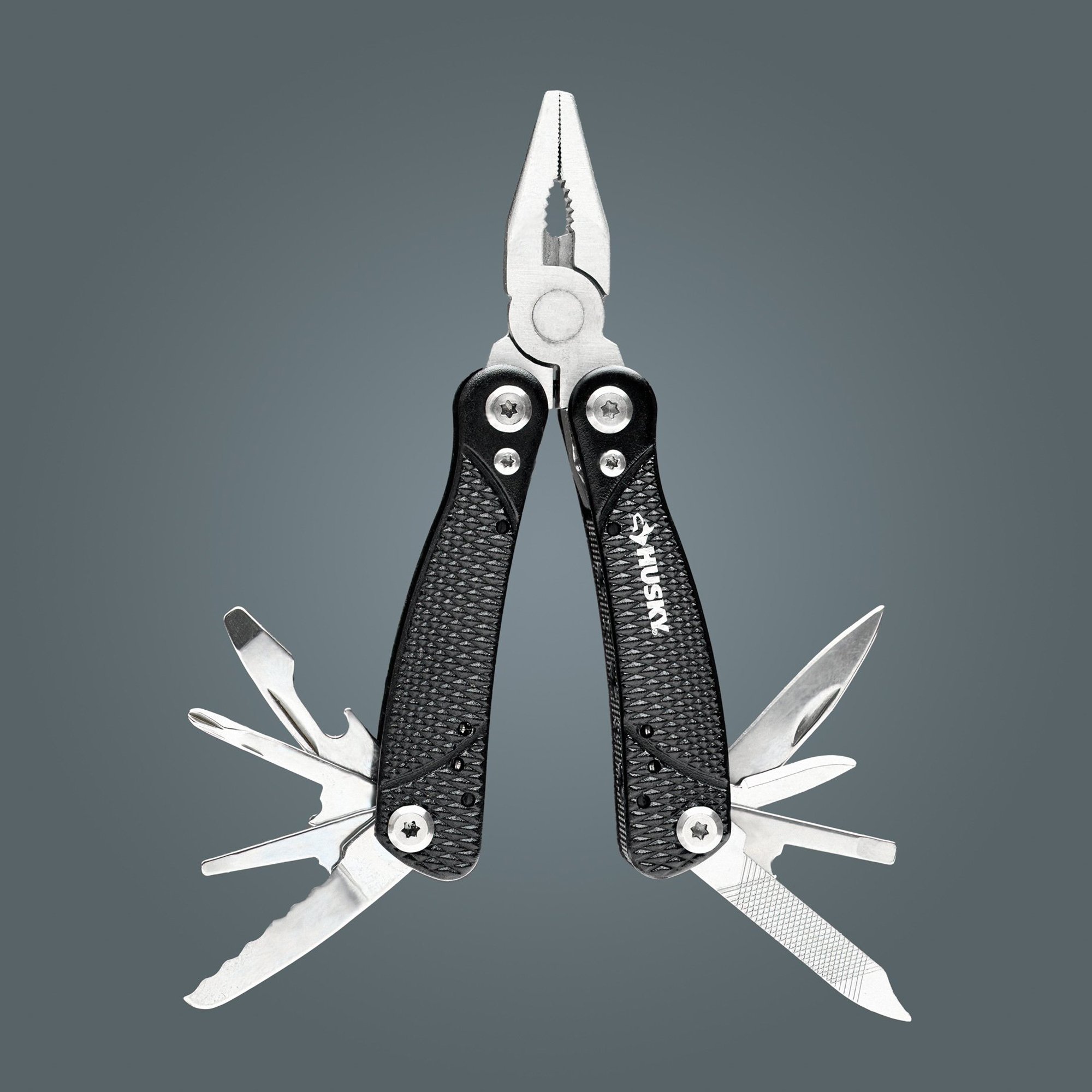  A leatherman-type tool was photographed showing all the tools open against a gray background. 