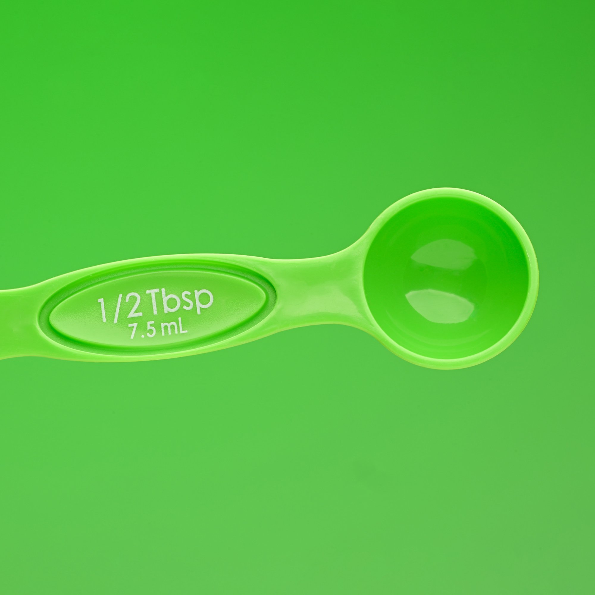  green on green a measuring spoon is photographed on a like green color, close up showing product detail 