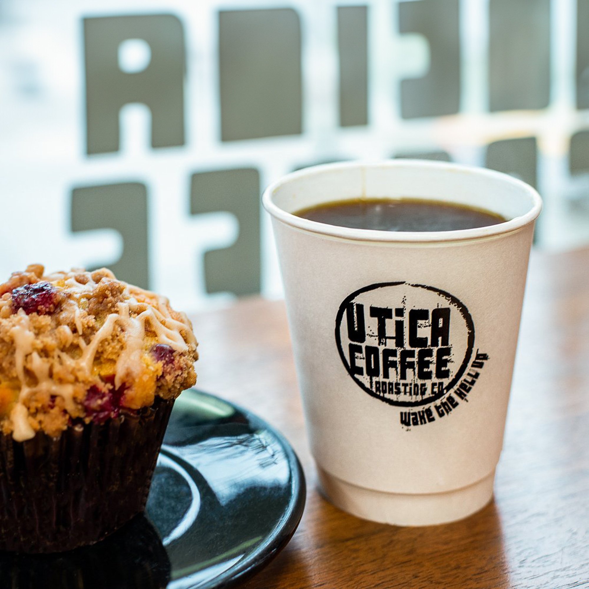  Coffee from a local coffee shop on a shelf by the window and a blueberry muffin 