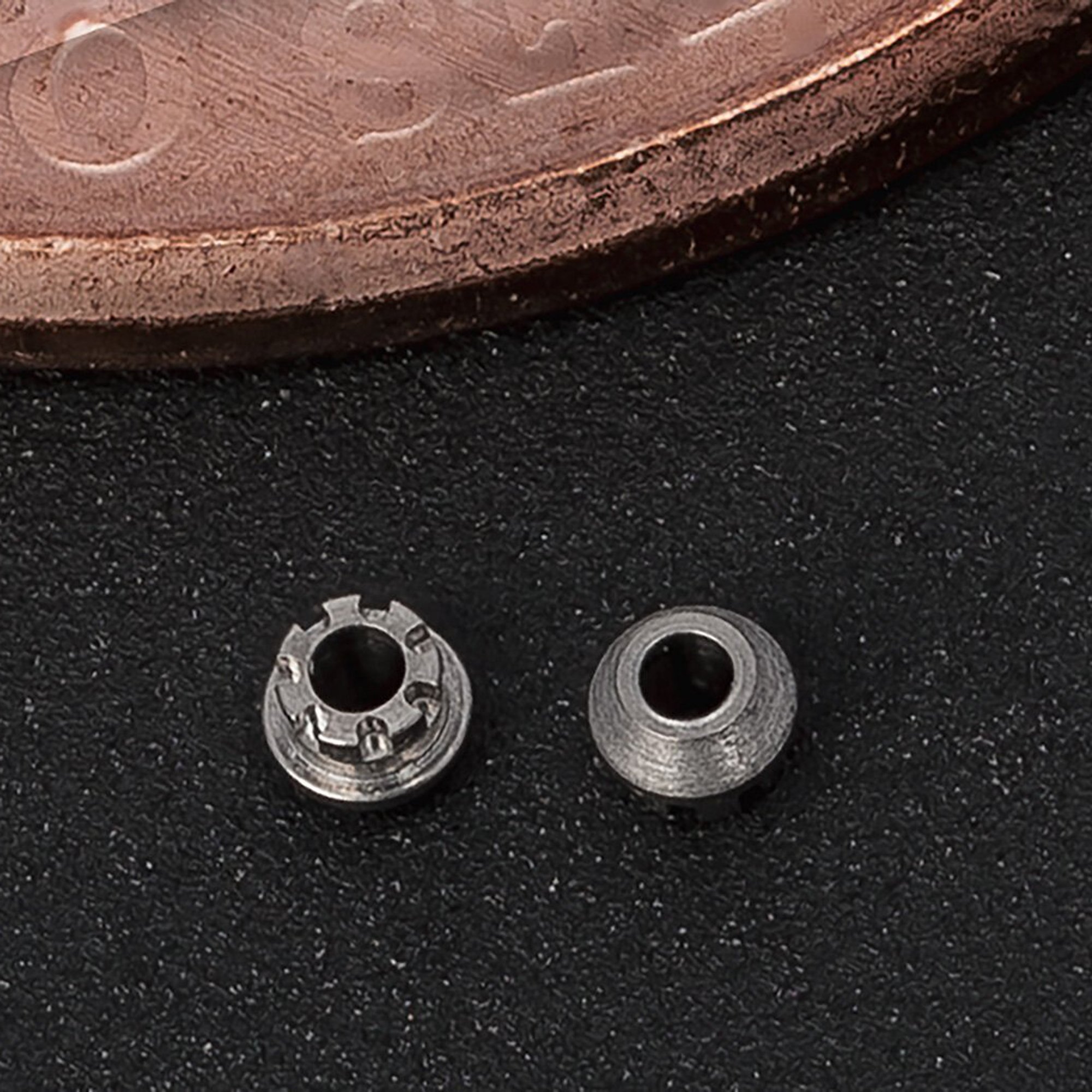  Closeup photograph of small machined parts next to a penny for scale. Details in the part are seen in the photo 