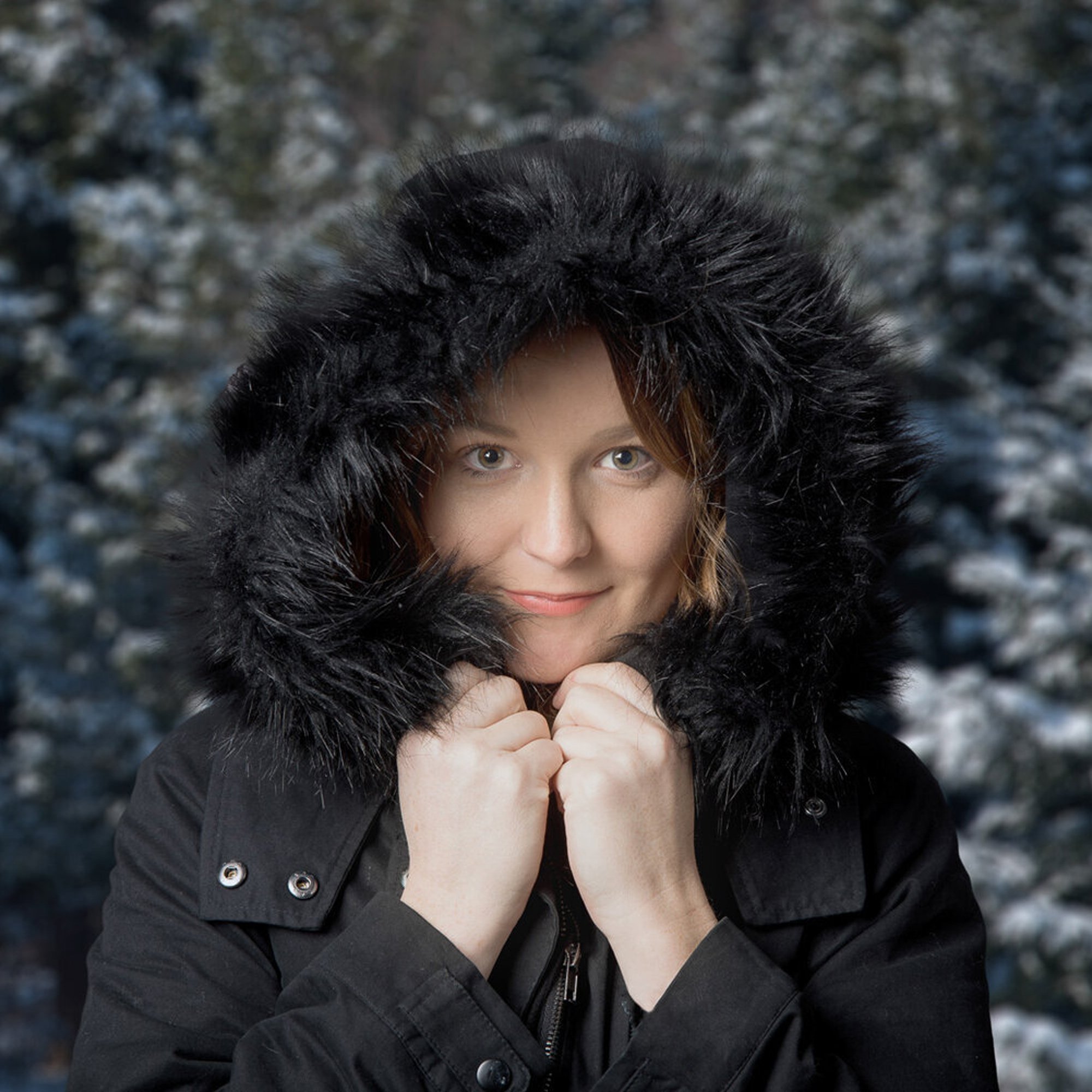  Photograph of a woman taken in studio showing off a fur-lined hooded black coat 