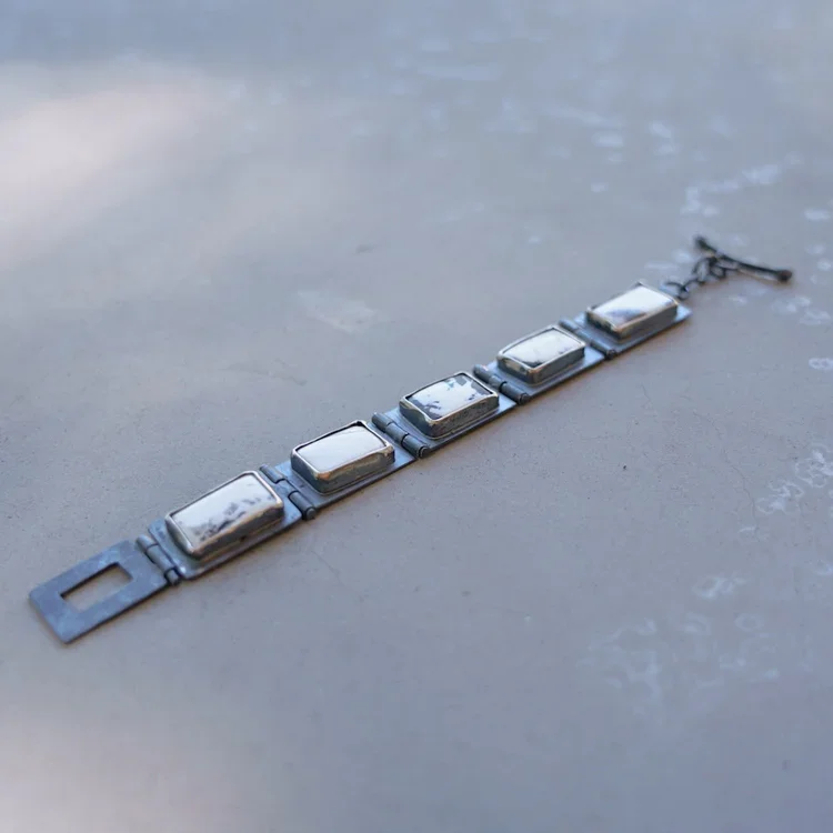 White Buffalo Dolomite Hinged Bracelet
This one of a kind bracelet is hand crafted with blackened (oxidized) sterling silver and White Buffalo Dolomite (the stones). Each link is individually handcrafted from sterling silver sheet metal. After formin