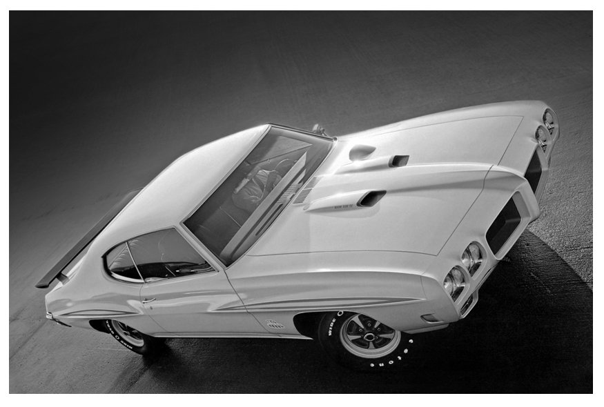 Black and white photo of a vintage sports car viewed from above, positioned on a flat surface.