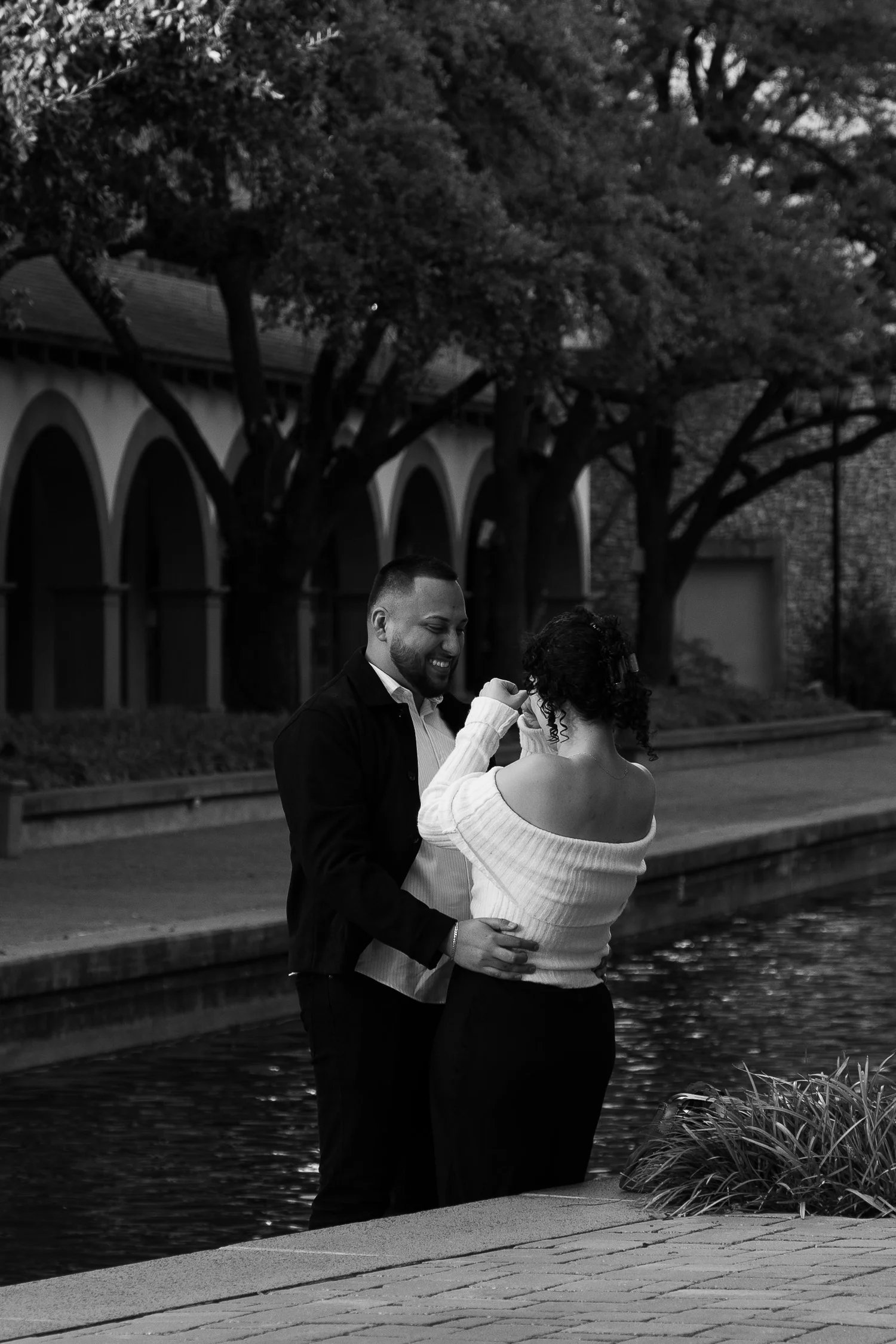 Engaged couple embracing beside the water