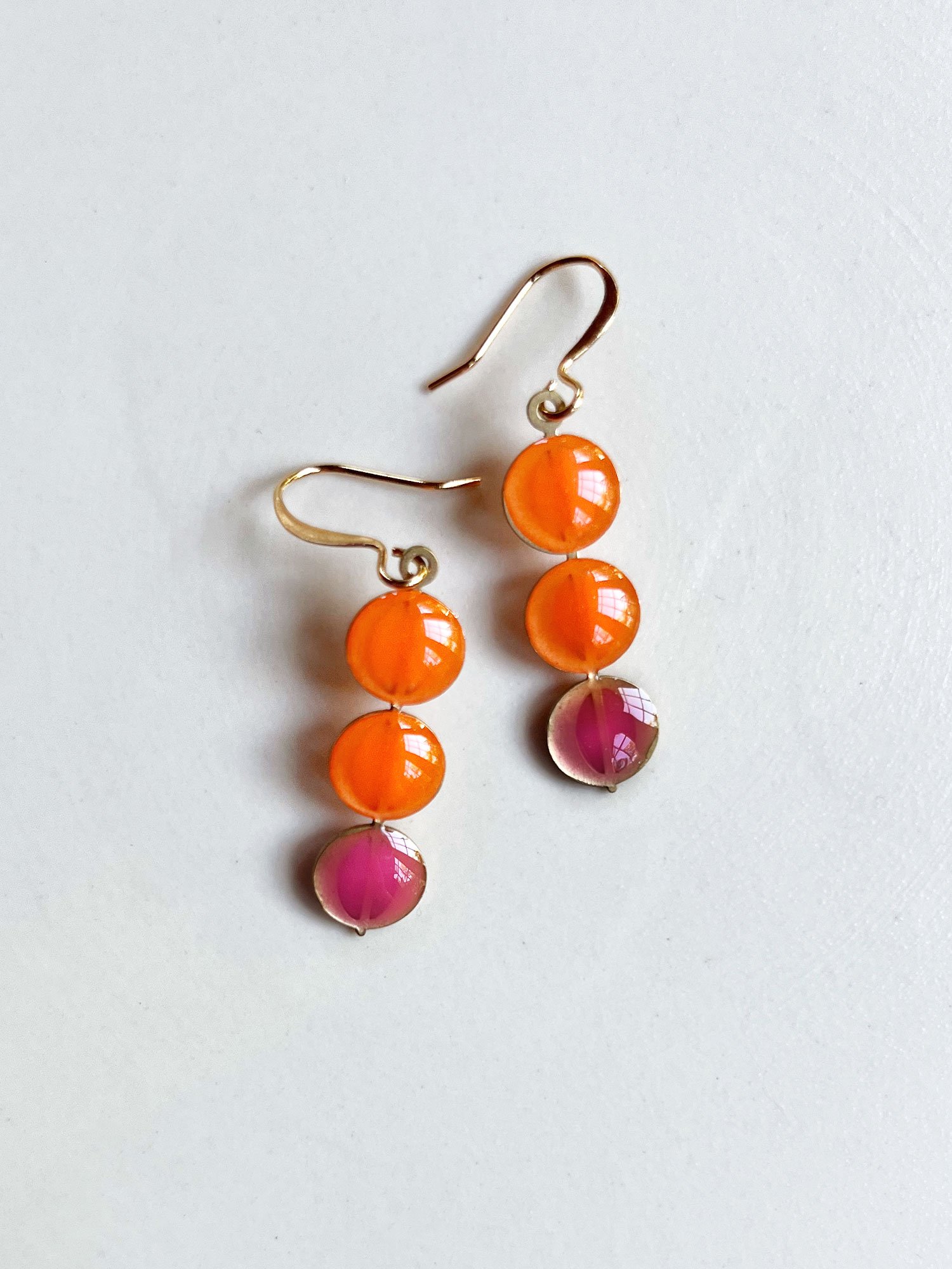 Three brass circles stacked with orange and pink.