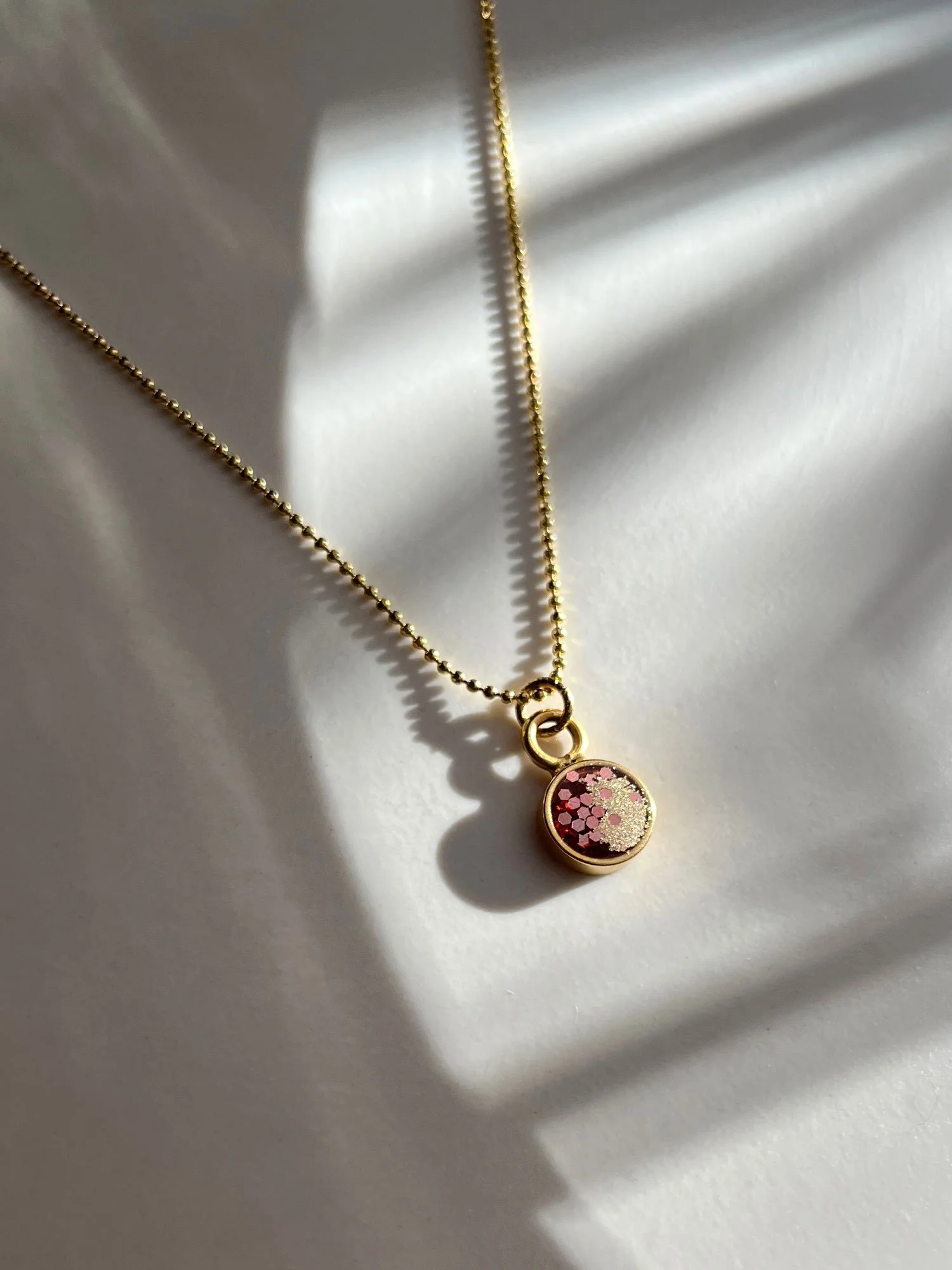 Strong sunlight on an orange and gold circle pendant necklace