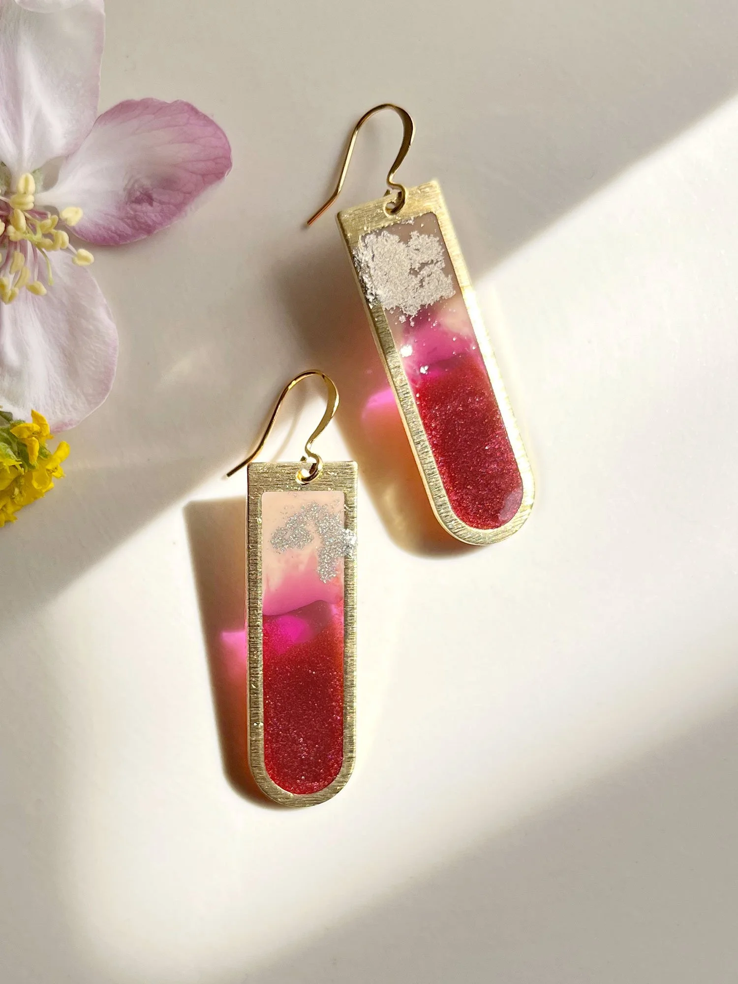 Long brass and resin earrings with red and pink rhubarb resin filling.