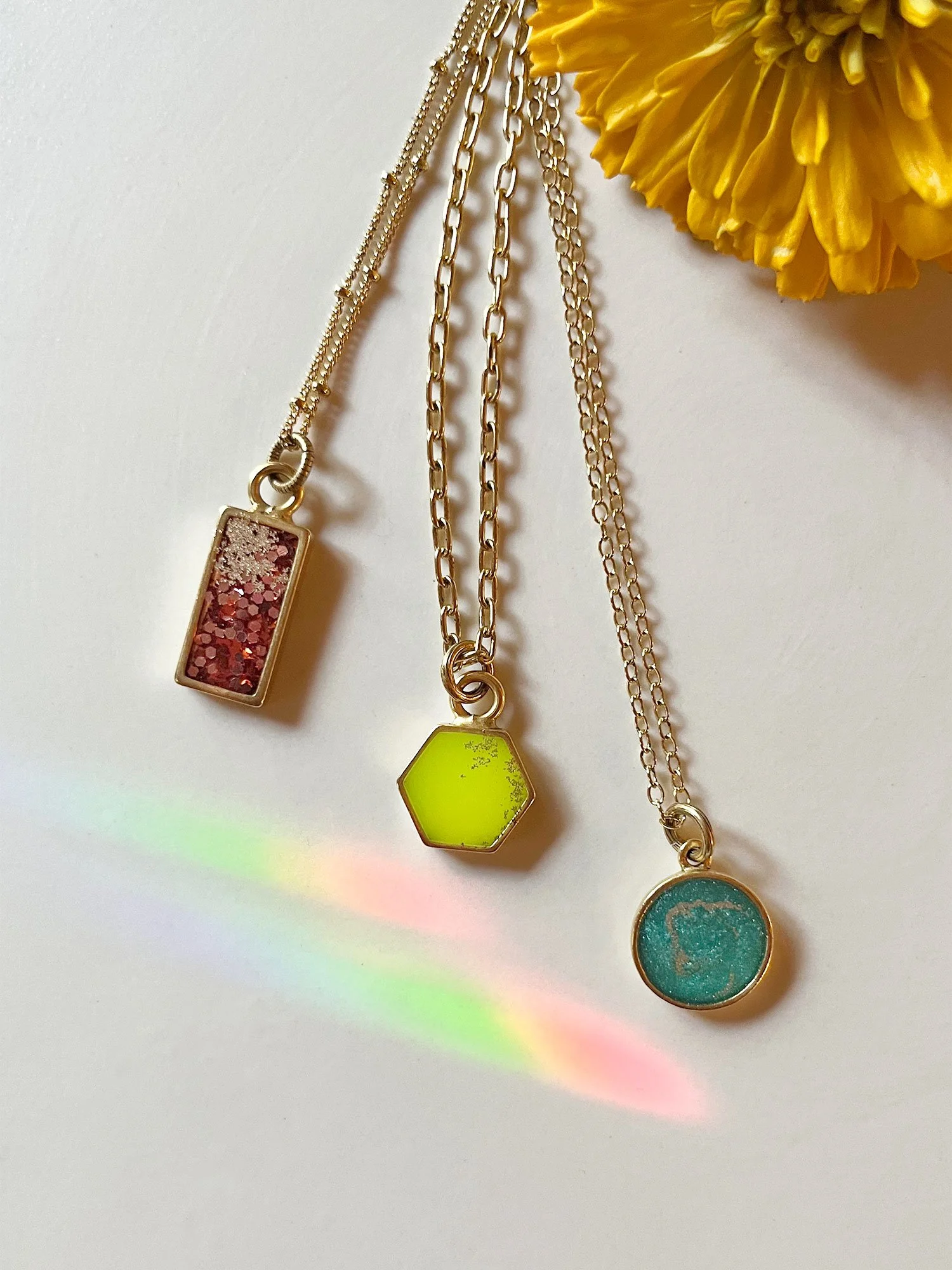 A lineup of three different-sized pendants and types of chain.