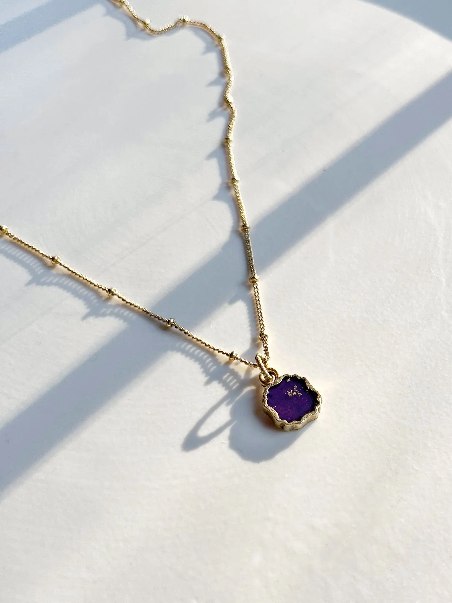 Strong sunlight shining on a gold clover pendant necklace