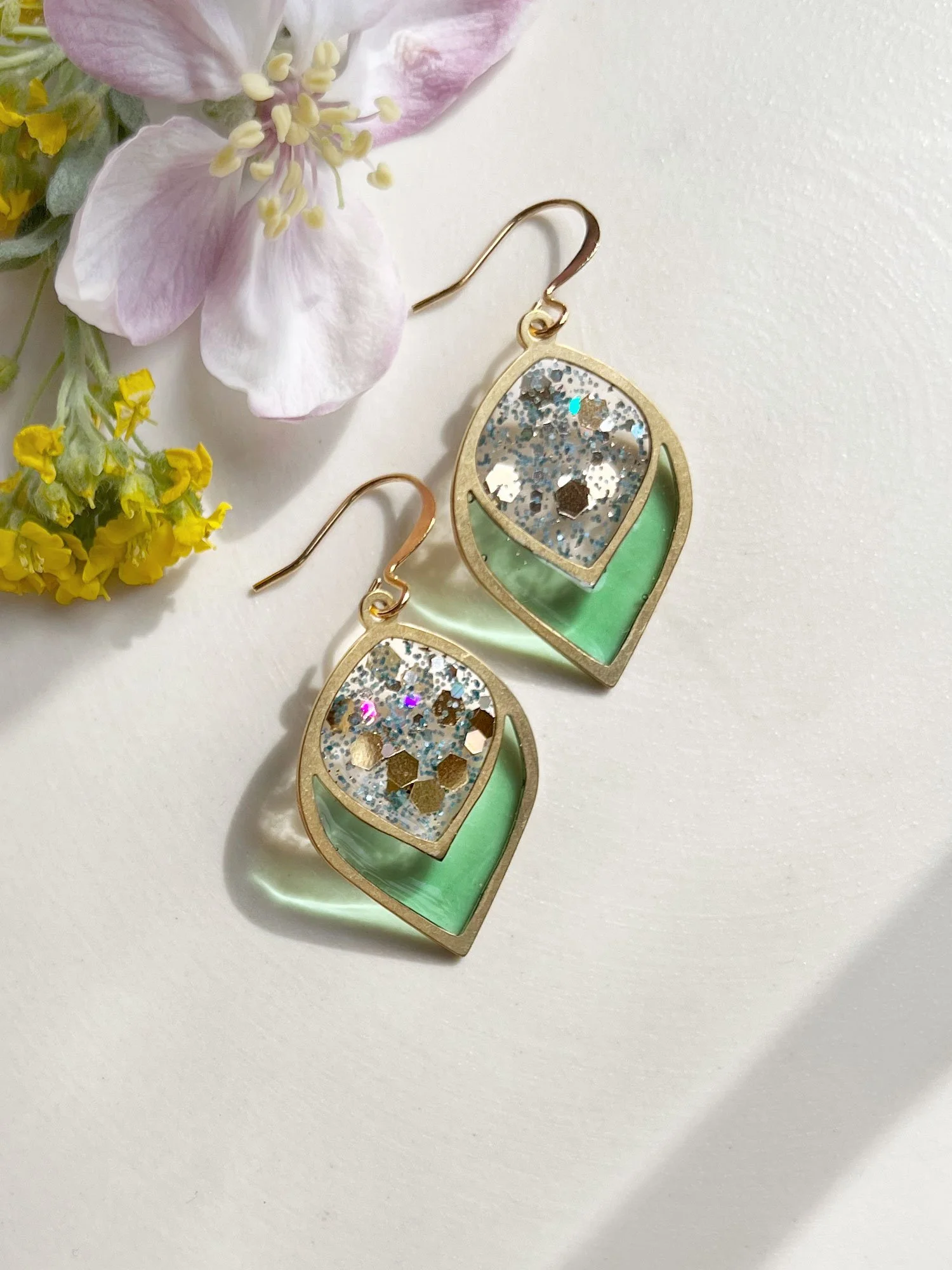Teardrop shaped brass earrings with green and blue sparkly center