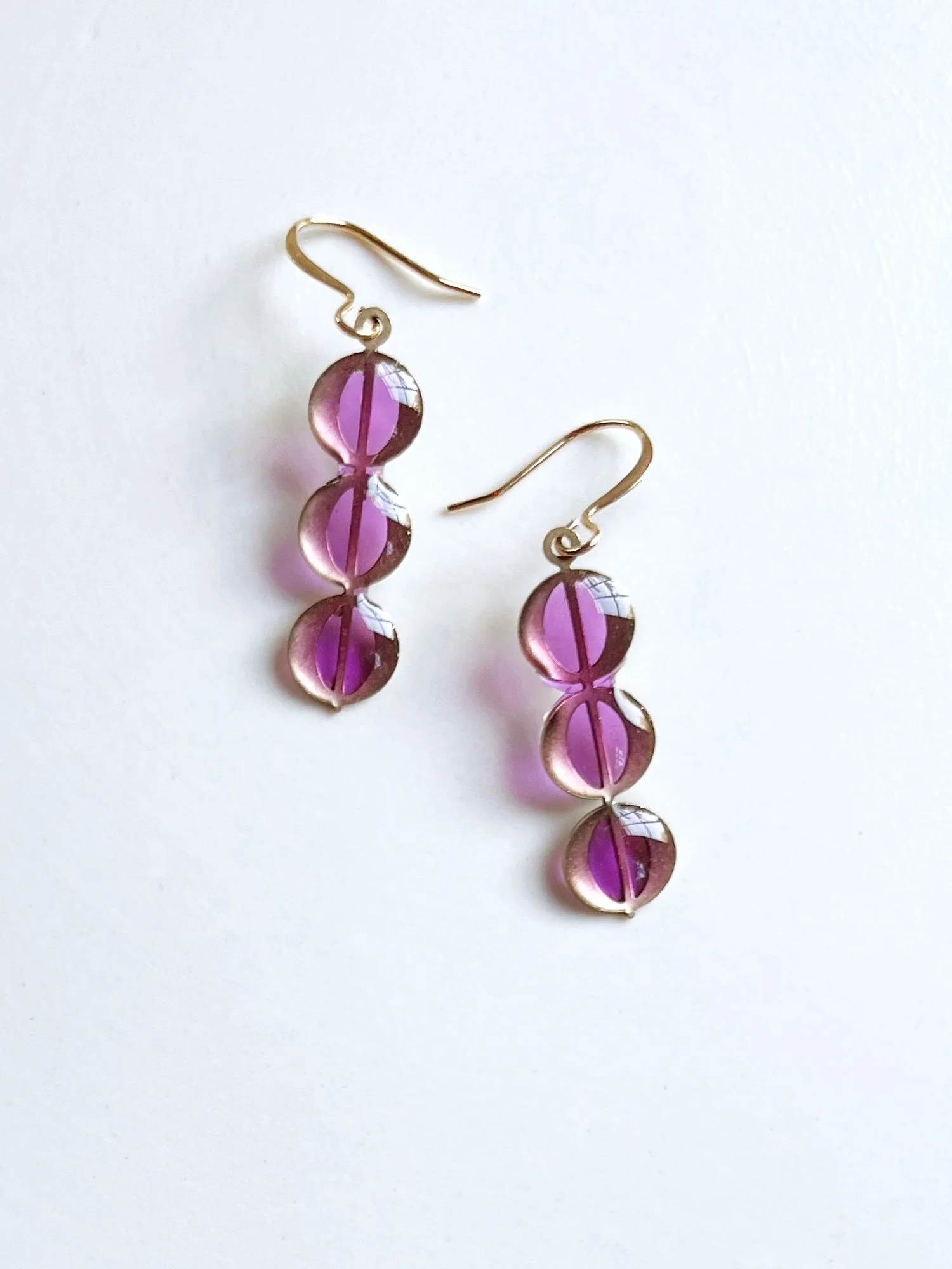 Column of brass circles with purple resin earrings.