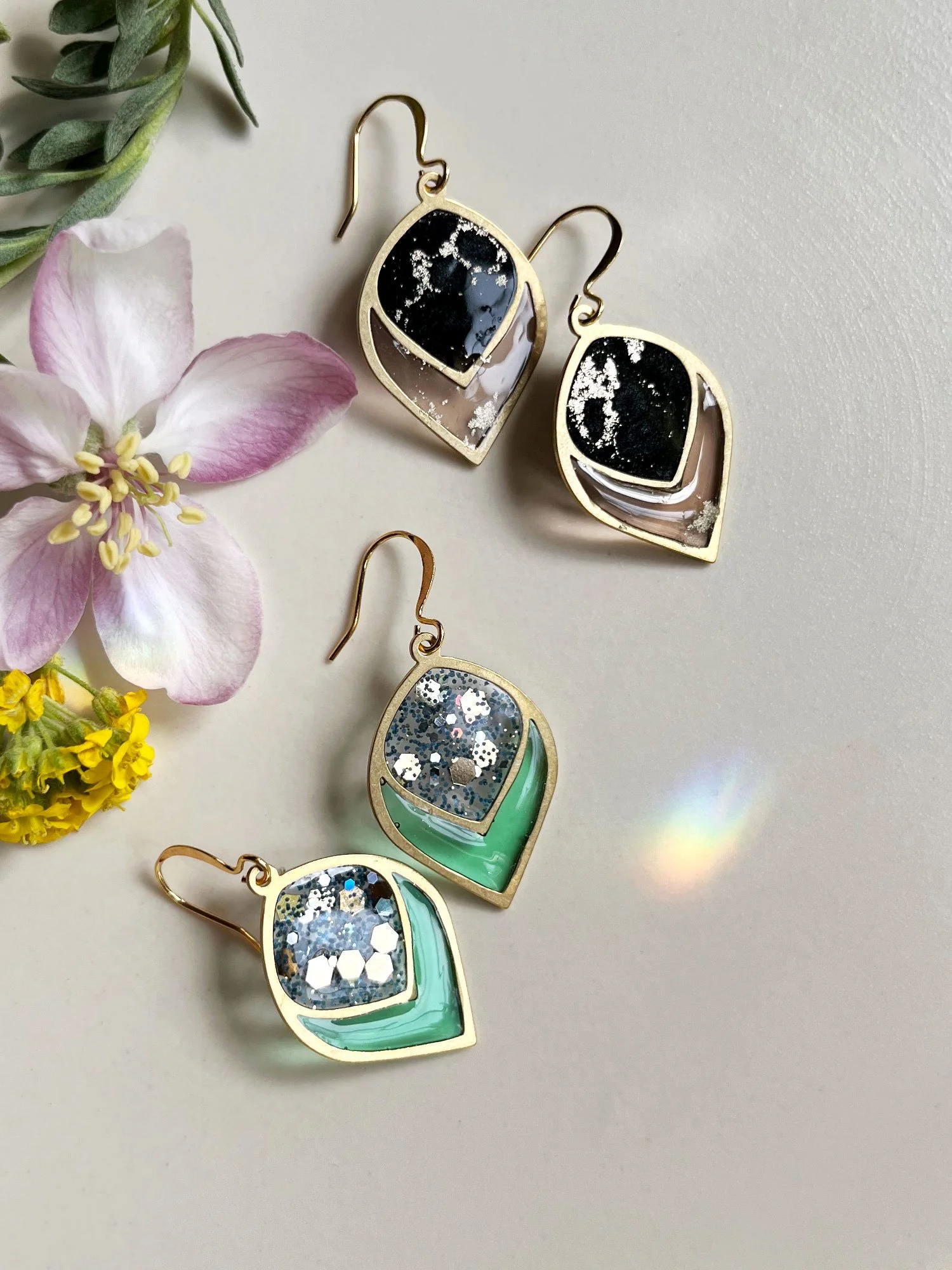 Two pairs of Mabel Earrings in strong sunlight with flowers