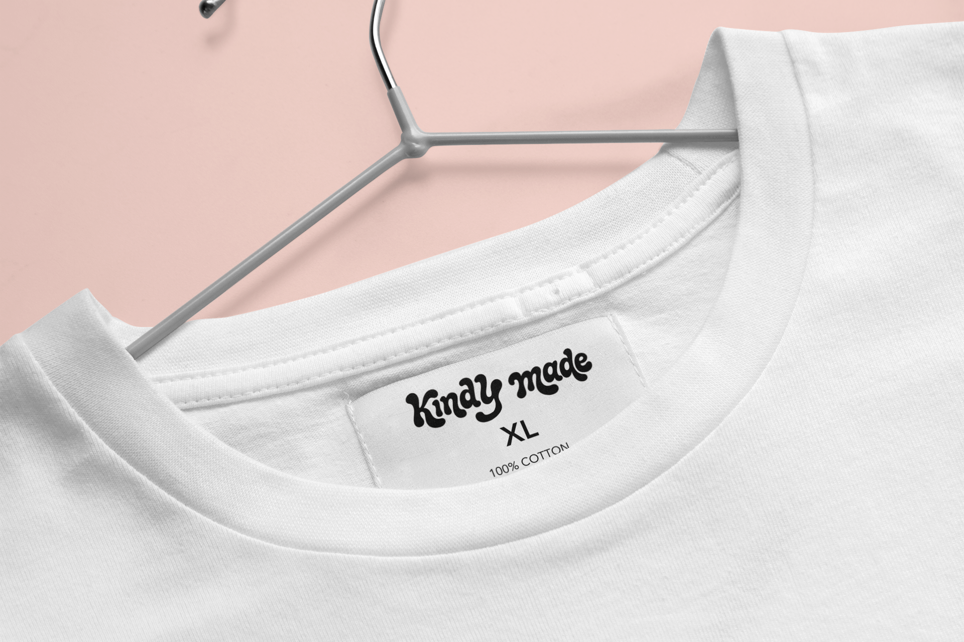 Close-up of a white T-shirt on a hanger, showing the neckline, tag with size XL, and fabric label indicating 100% cotton.