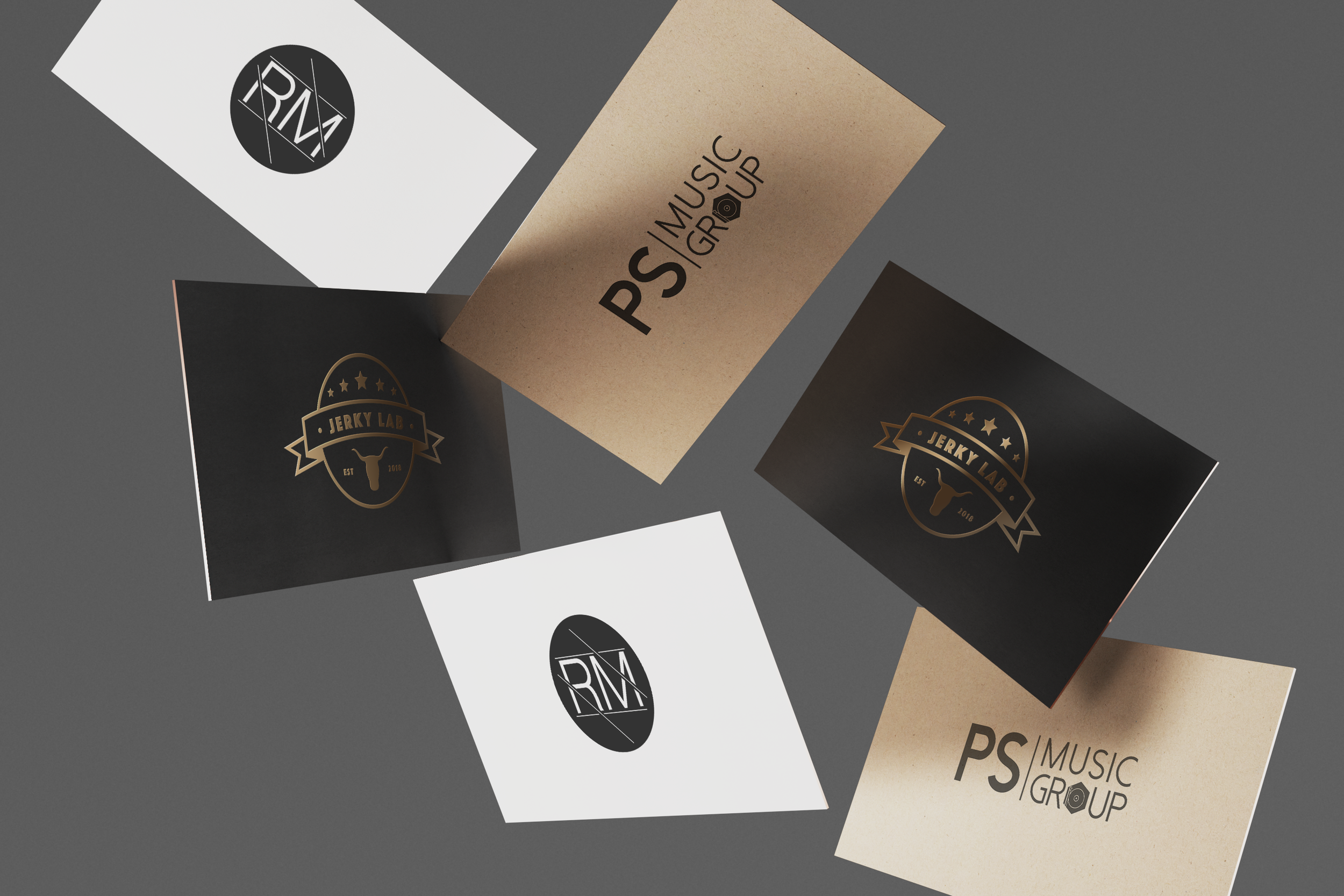 Multiple business cards spread out on a gray surface. The cards include designs with logos and text for a music group and a jerky lab.