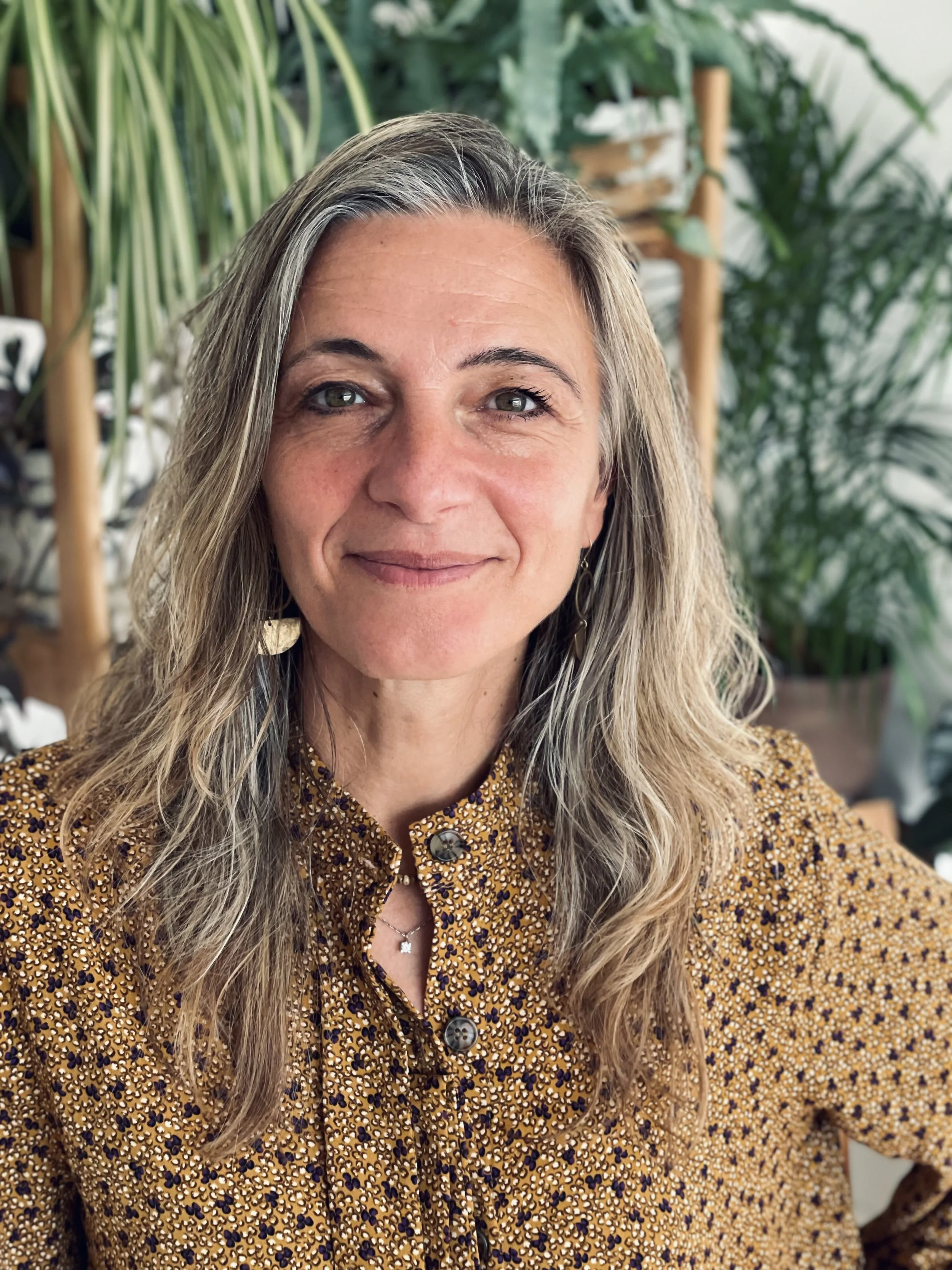 Vera Braghiroli, integrative counsellor, smiling, surrounded by houseplants
