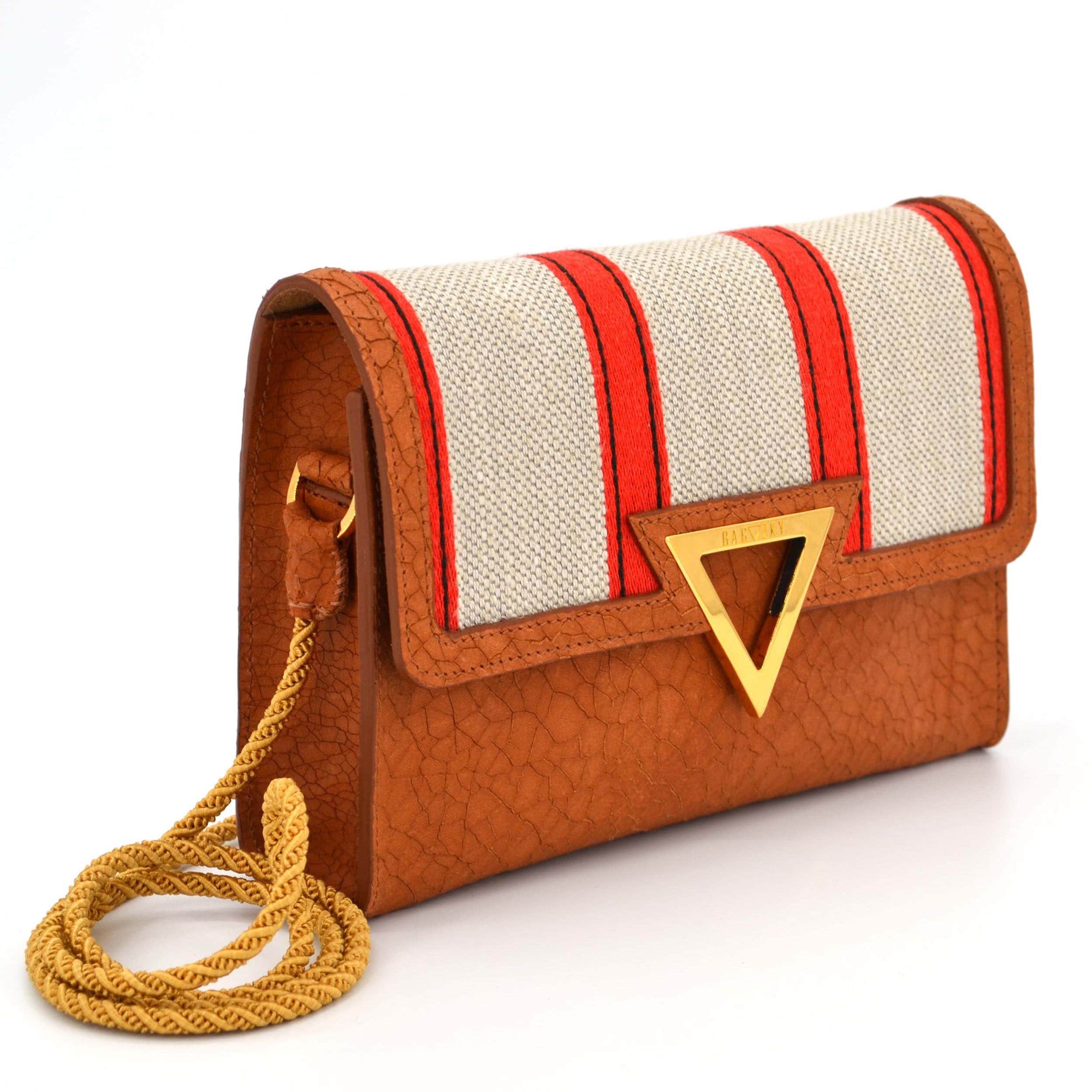 Side view of the cognac shoulder bag. The bag itself is a onecut, with the side panels inserted. The handels are made of handturned passament cord.
