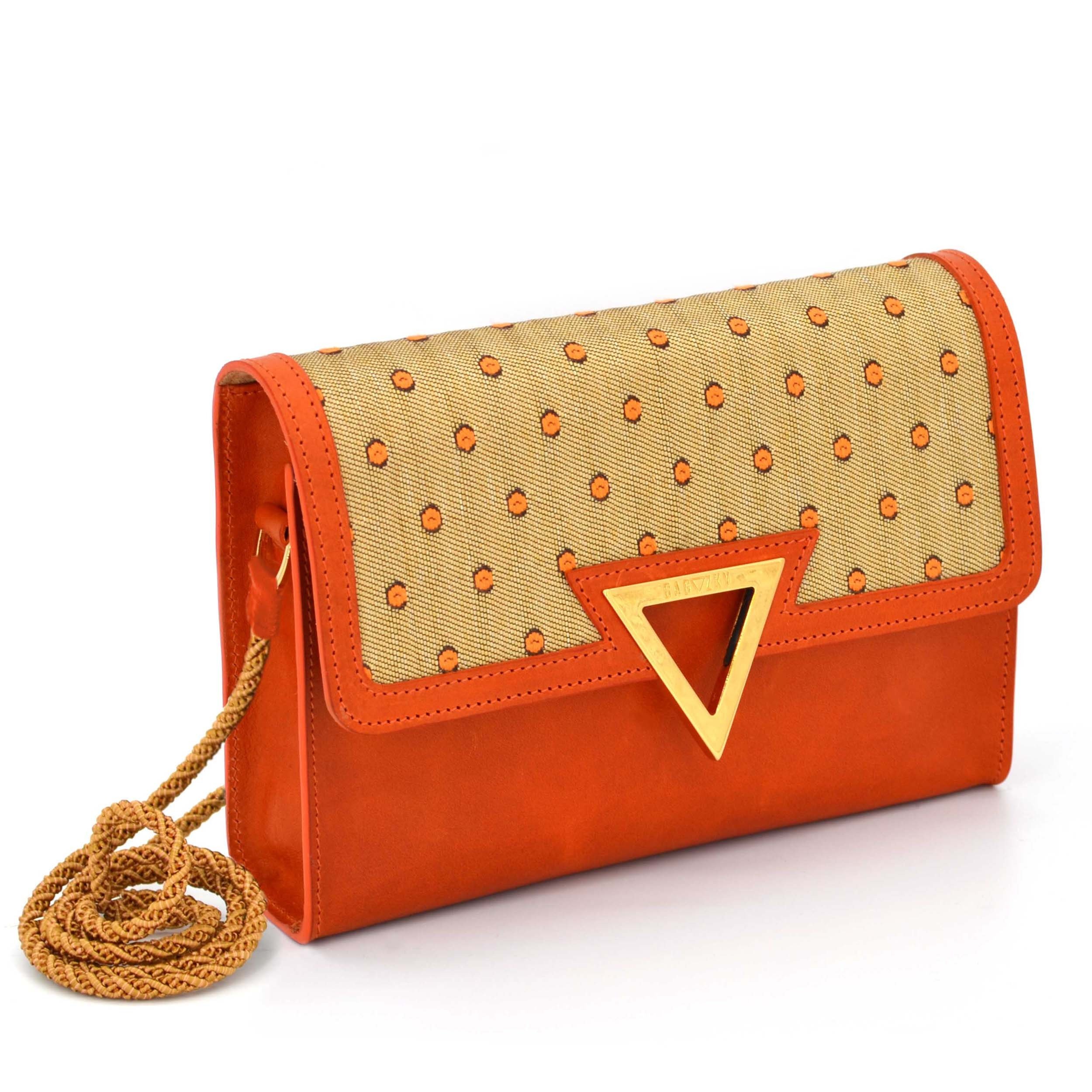 Side view of the Apricot Tappezzeria Clutch, which is made out of orange leather and dottet golden furniture fabric.