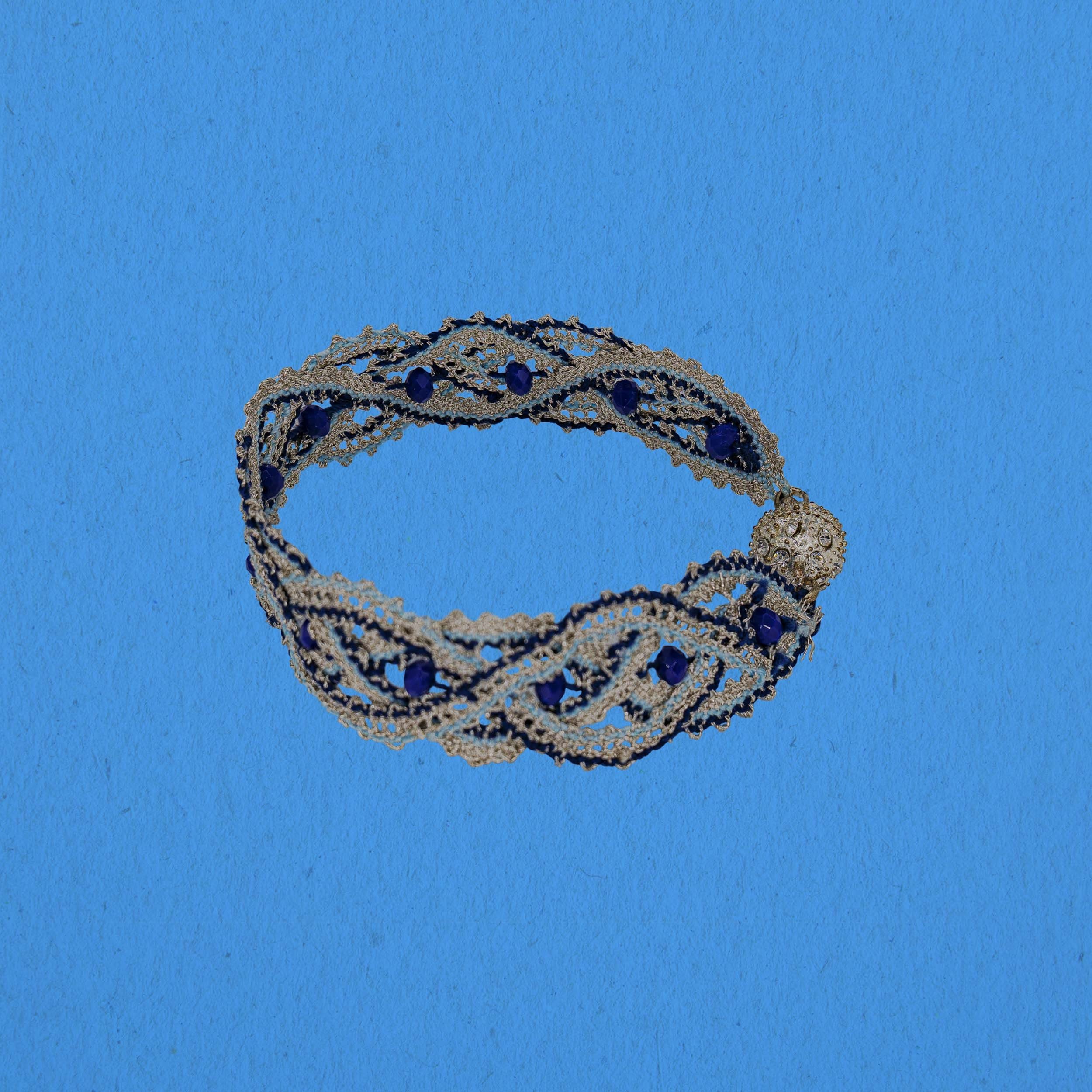 Bobbinlace wristband infront of blue background.