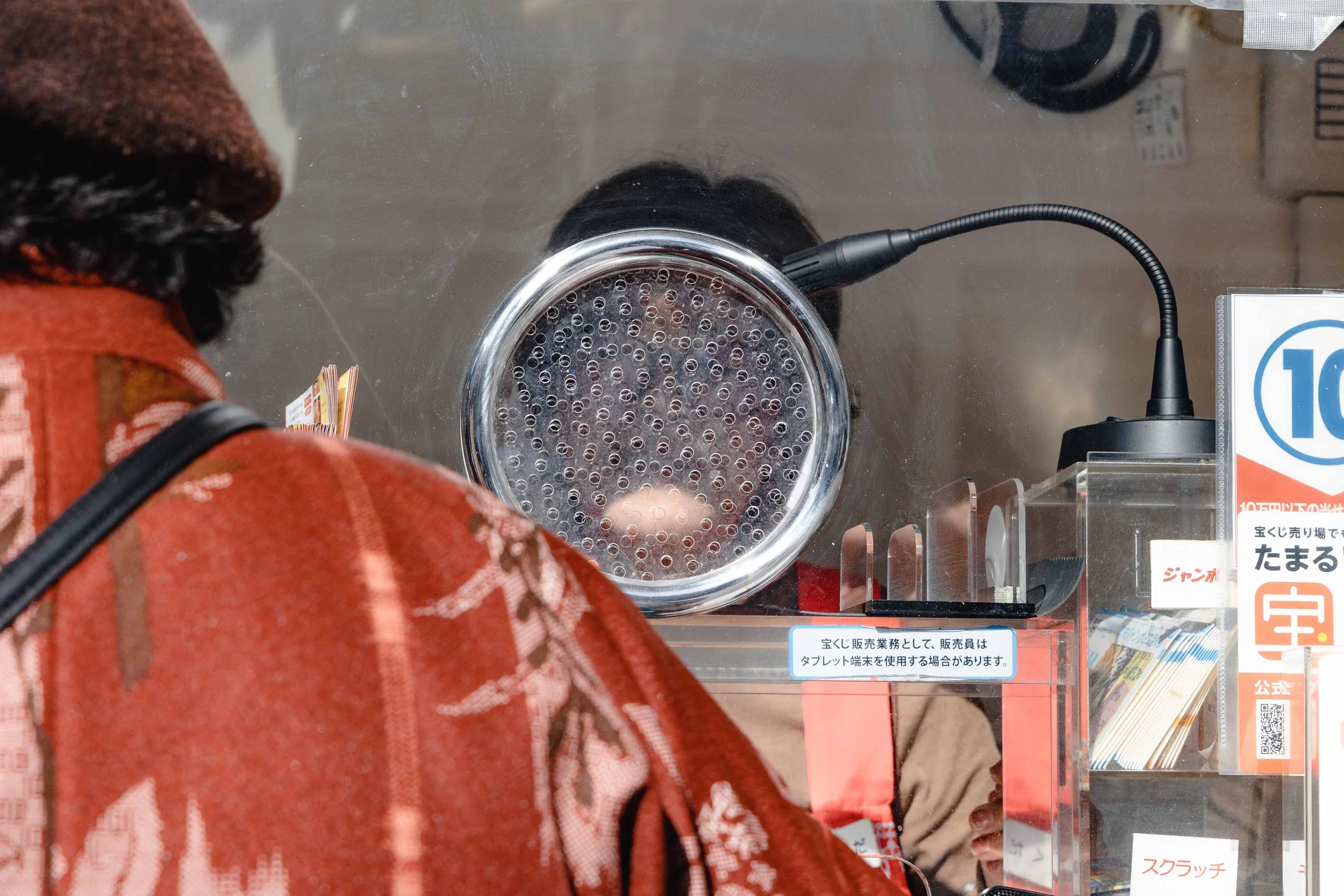 Man at a ticket counter in Kyoto. You can see the worker behind the counter through the holes in the glass
