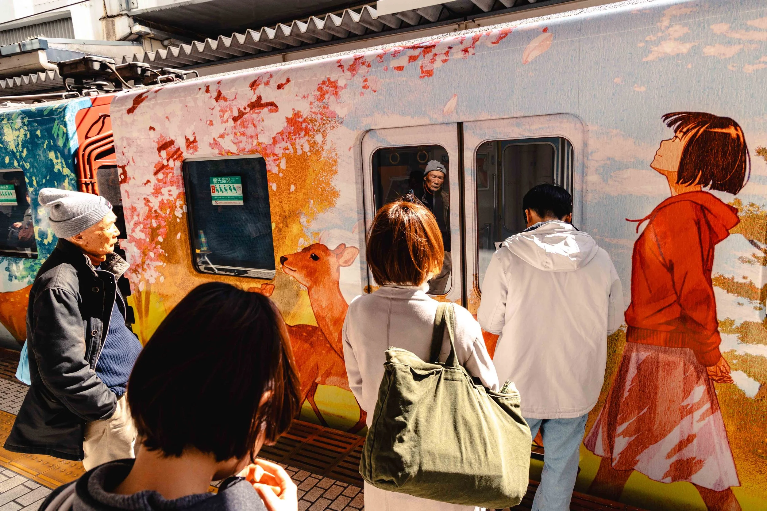 People waiting to board the colorful train that goes from Kyoto to Nara