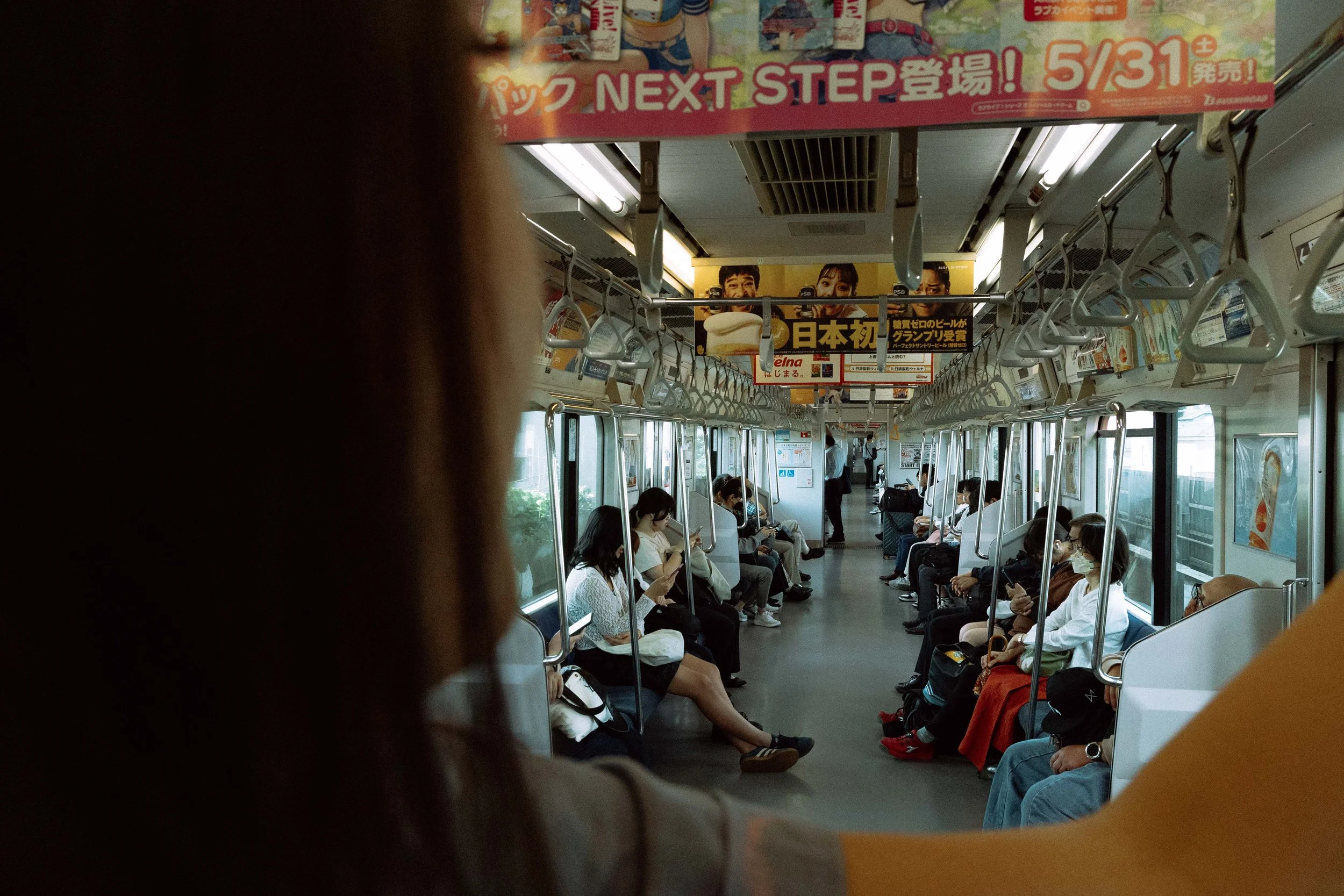 Photo of the inside of the JR train from Tokyo to Kamakura showing people sitting both to the left and right of the train.