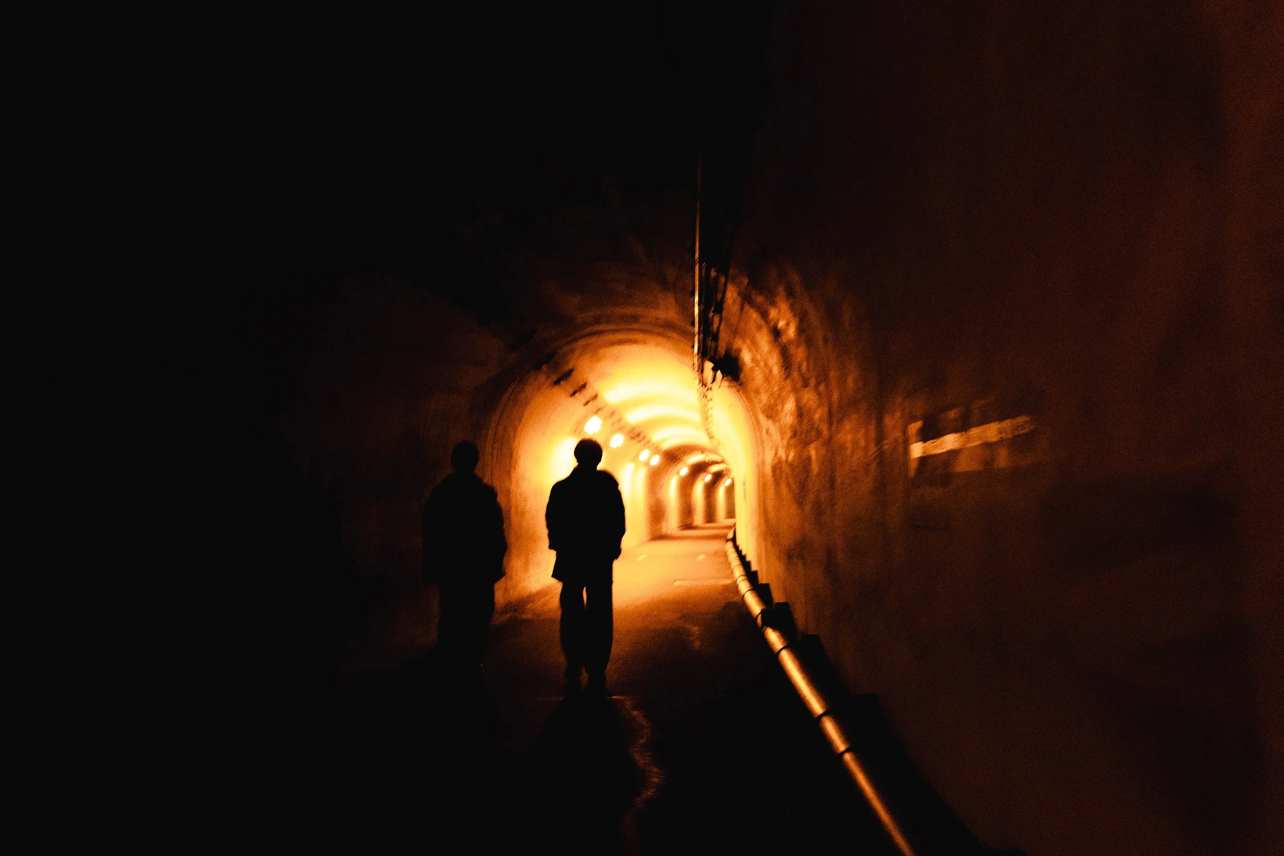 Kiyotsu Gorge Tunnel in the dark with the silhouettes of two people walking