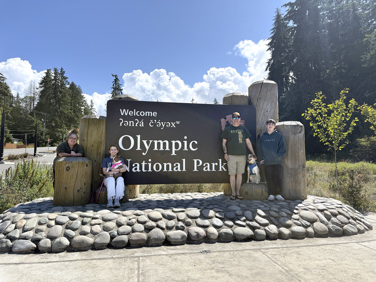 Family at Olympic National Park entrance sign.