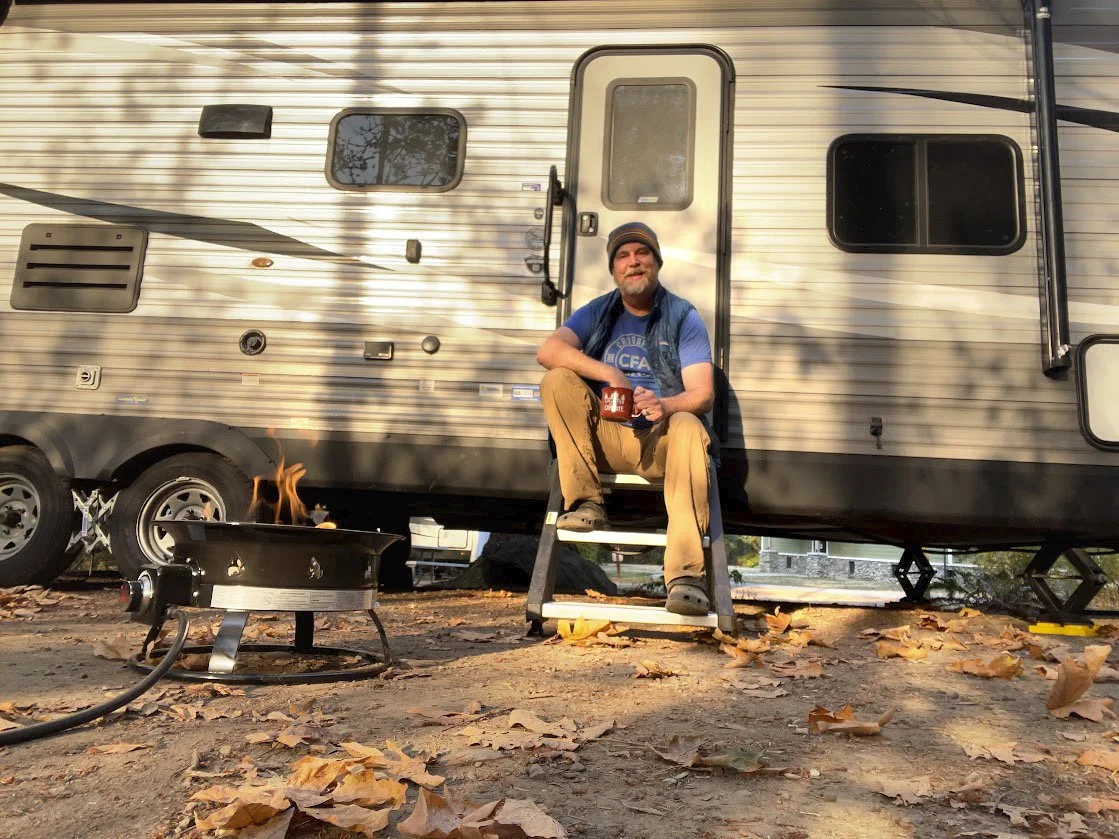 Podcast host, Brooks, sitting on steps of his rv during an autumn camping trip.