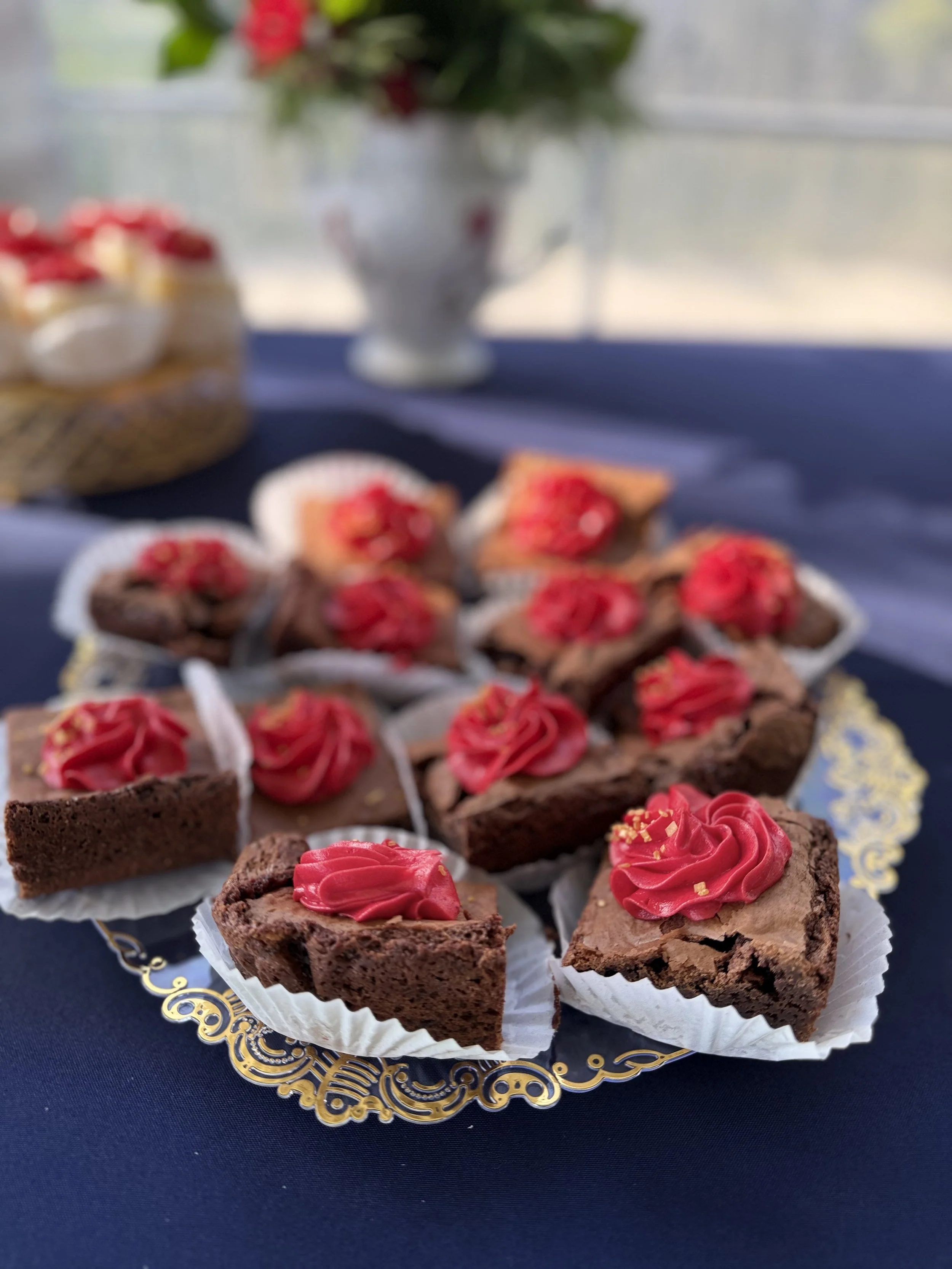 bite sized brownies topped with a red buttercream swirl and gold sugar dust