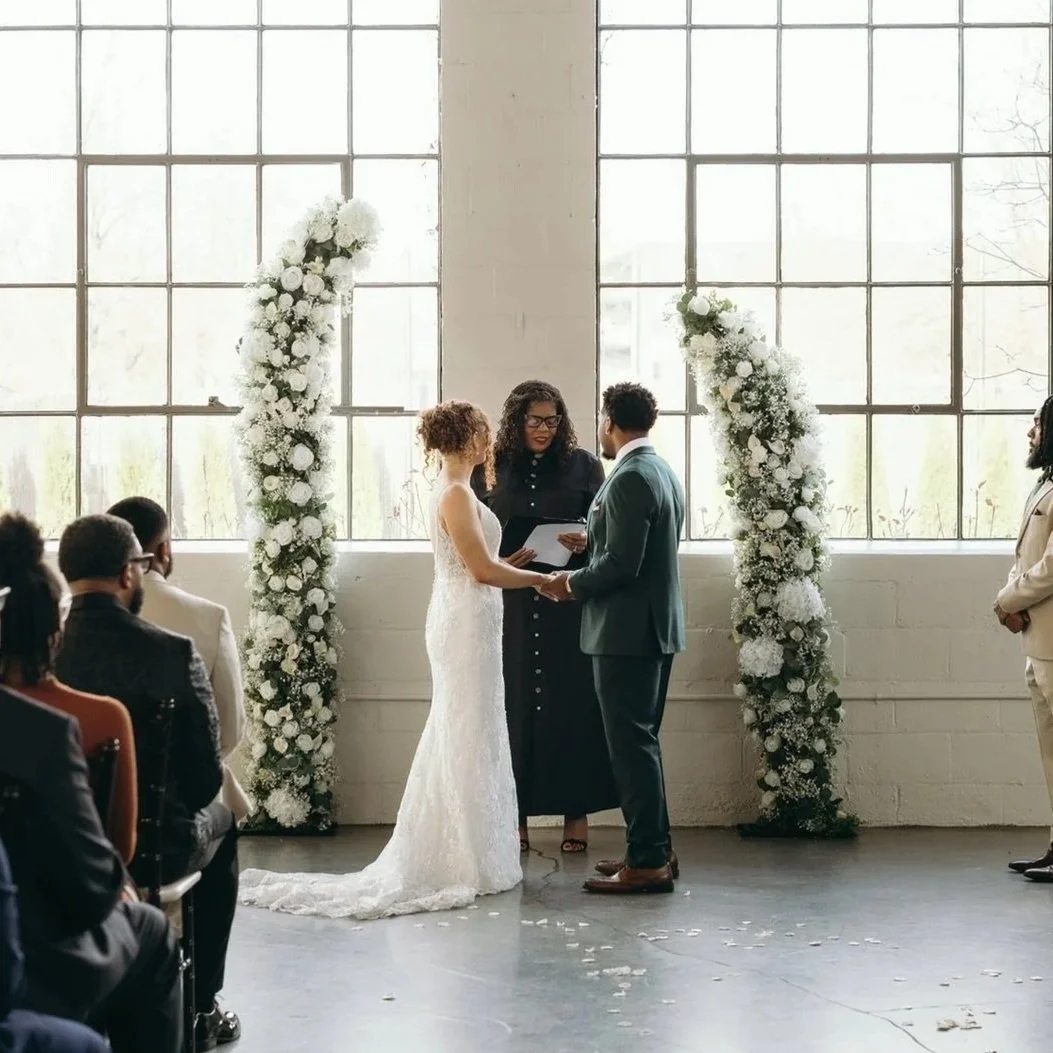bride and groom in front of greenery and white floral horn arch at The Clerestory Lexingon KY