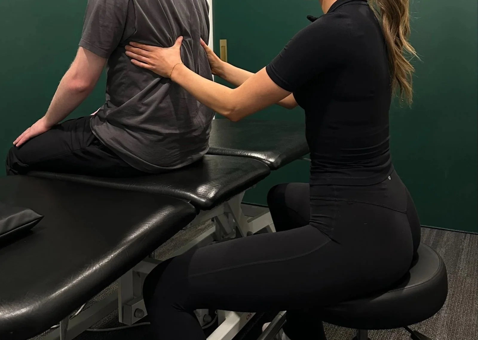 osteopathic manual practitioner performing a hands on assessment touching a persons back
