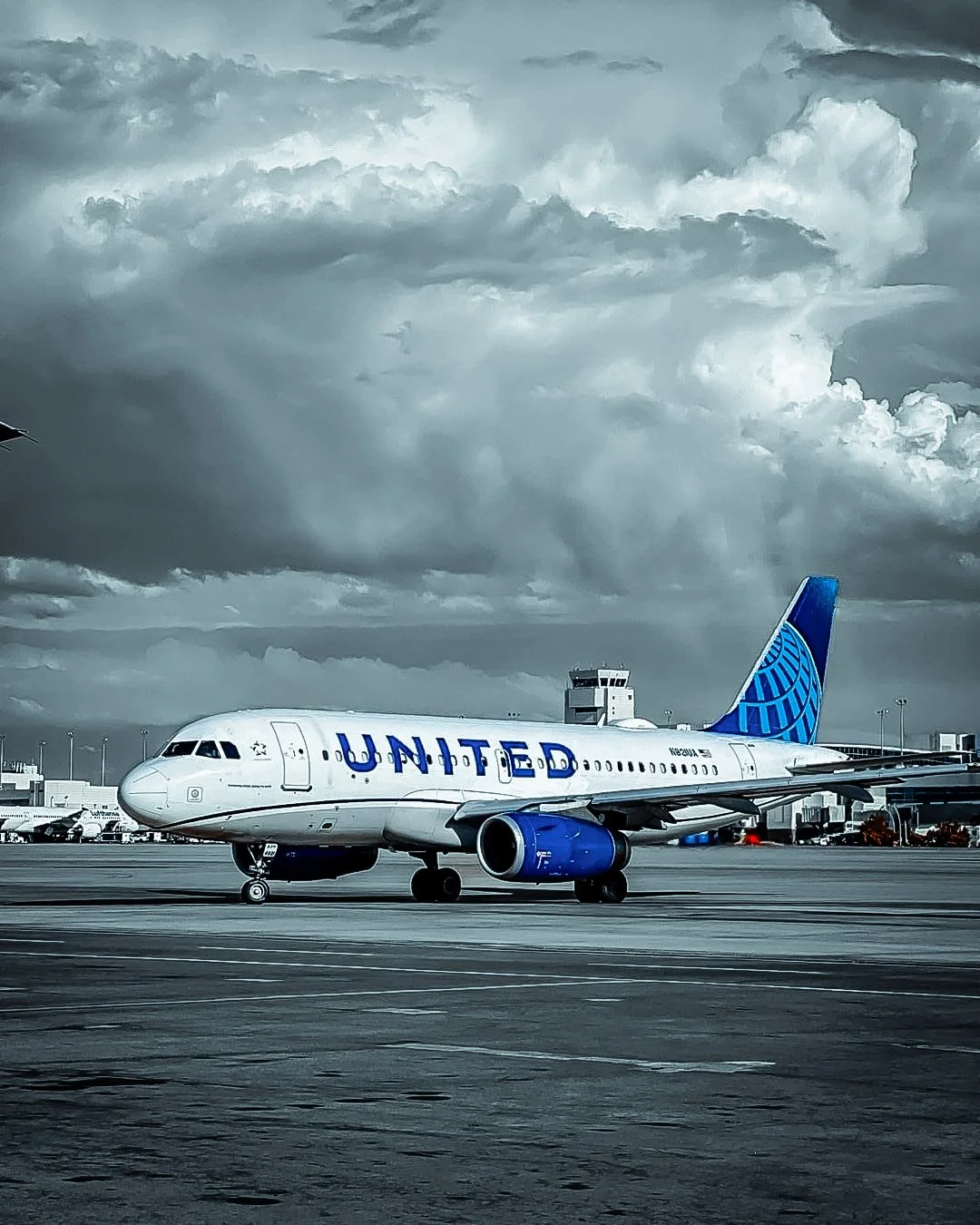 United Airlines airplane on tarmac under cloudy sky at an airport.